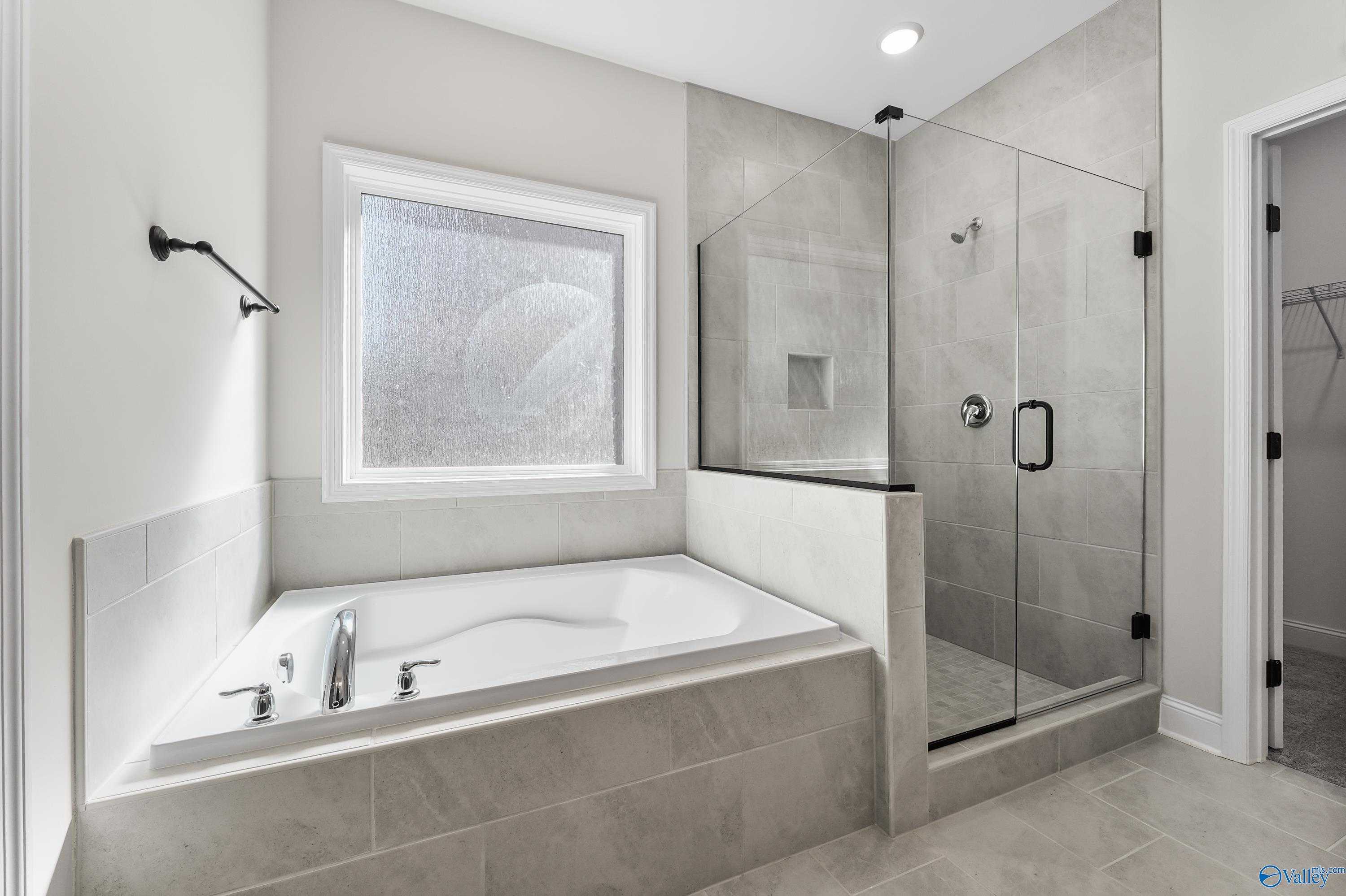 Modern master bathroom featuring freestanding tub, glass walk-in shower, and frosted window in Davidson Homes The Montgomery C, Decatur, Alabama