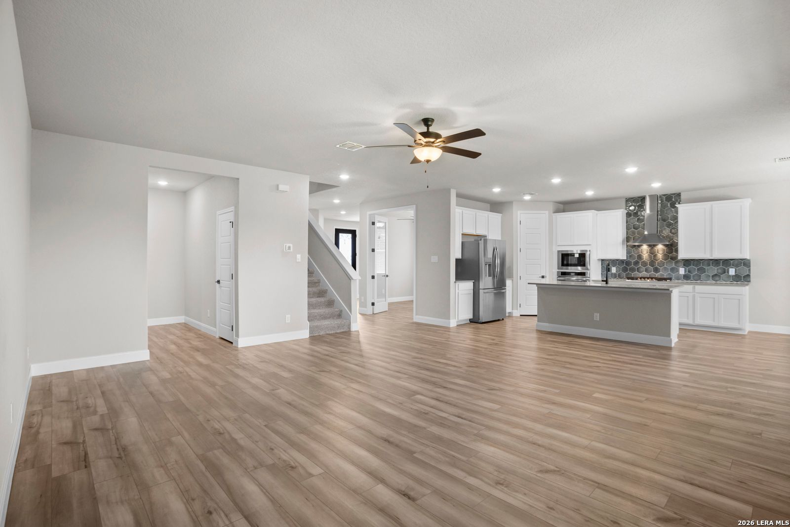 Open-concept living room and kitchen with white cabinets in The Jennings G floor plan by Davidson Homes in San Antonio.