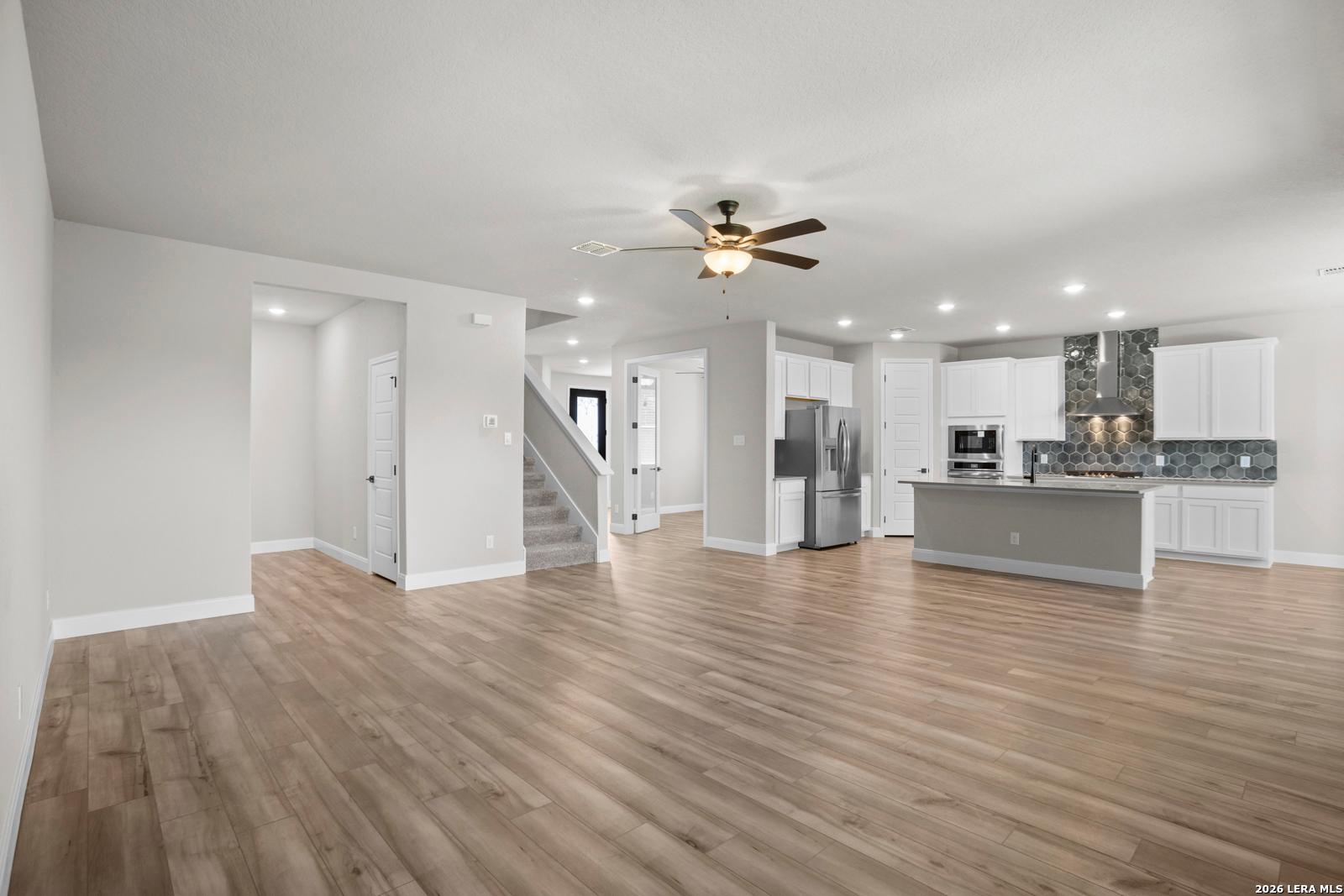 Open-concept living room and kitchen with white cabinets in The Jennings G floor plan by Davidson Homes in San Antonio.