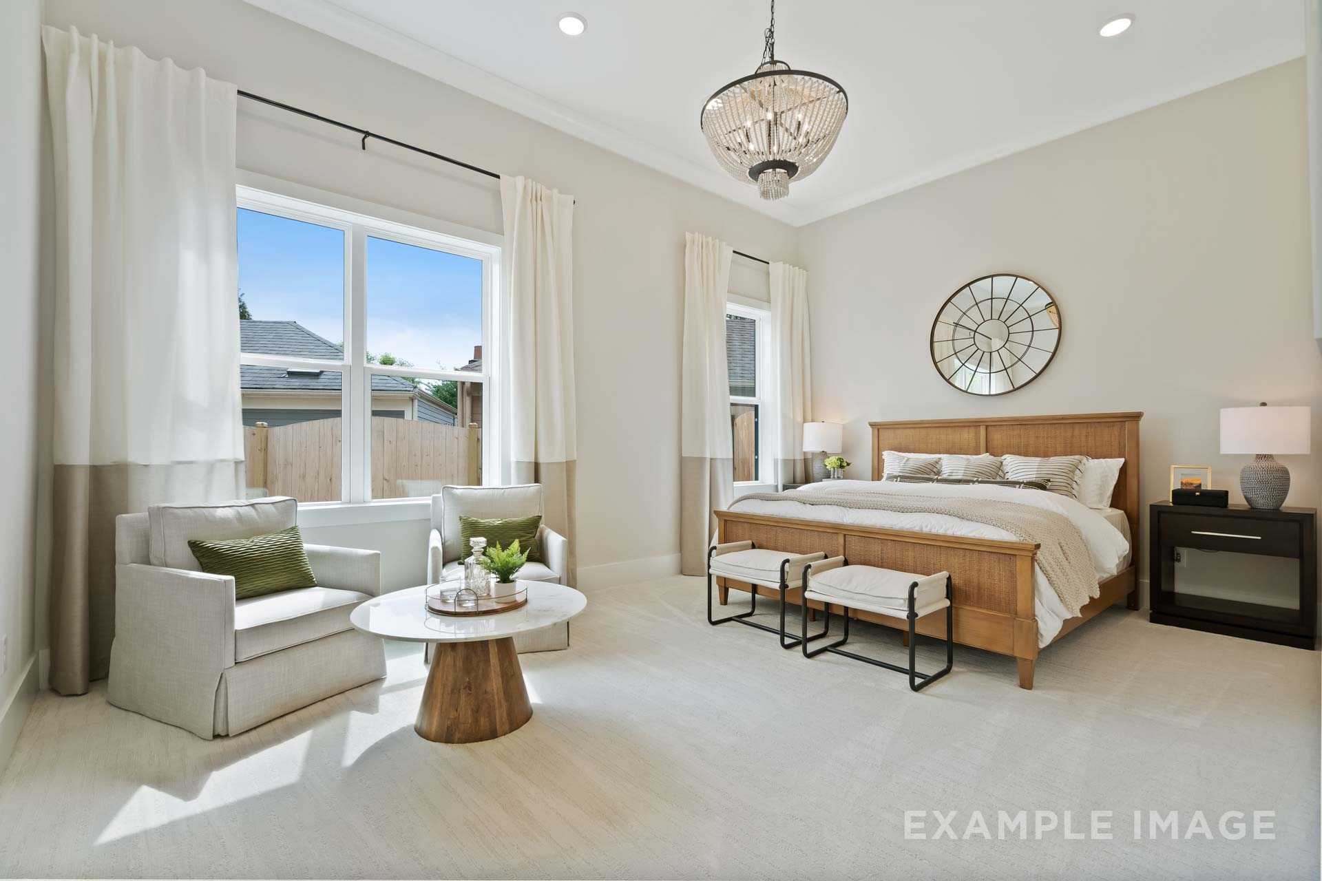 Spacious primary bedroom at Manor Estates in Marietta GA with king bed, chandelier, large windows, and neutral decor