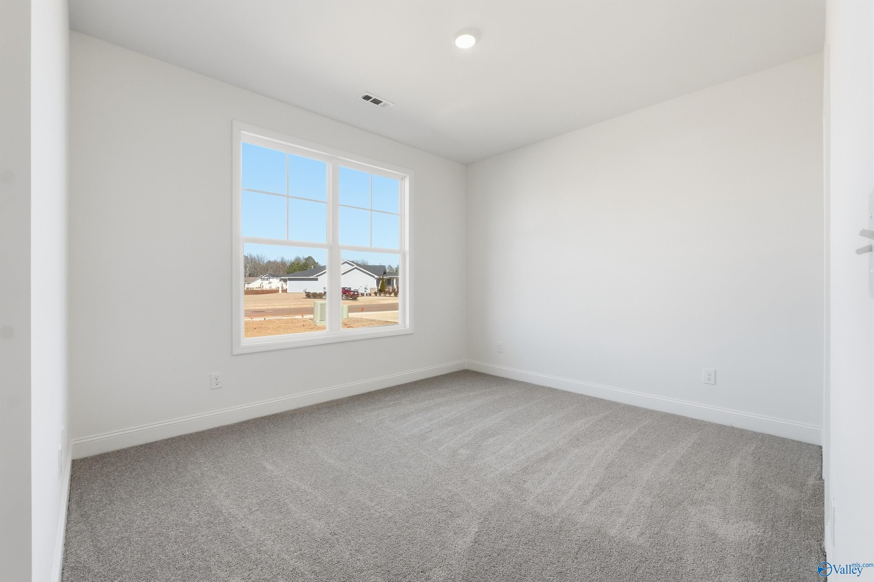 Bright secondary bedroom with large window and gray carpet in Davidson Homes The Rockford D, Hazel Green, Alabama