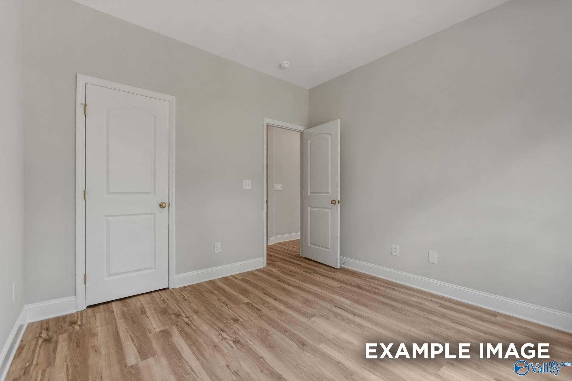 Cozy secondary bedroom featuring gray walls, white doors to bath, hardwood floors in Davidson Homes The Shelby C, Meridianville AL