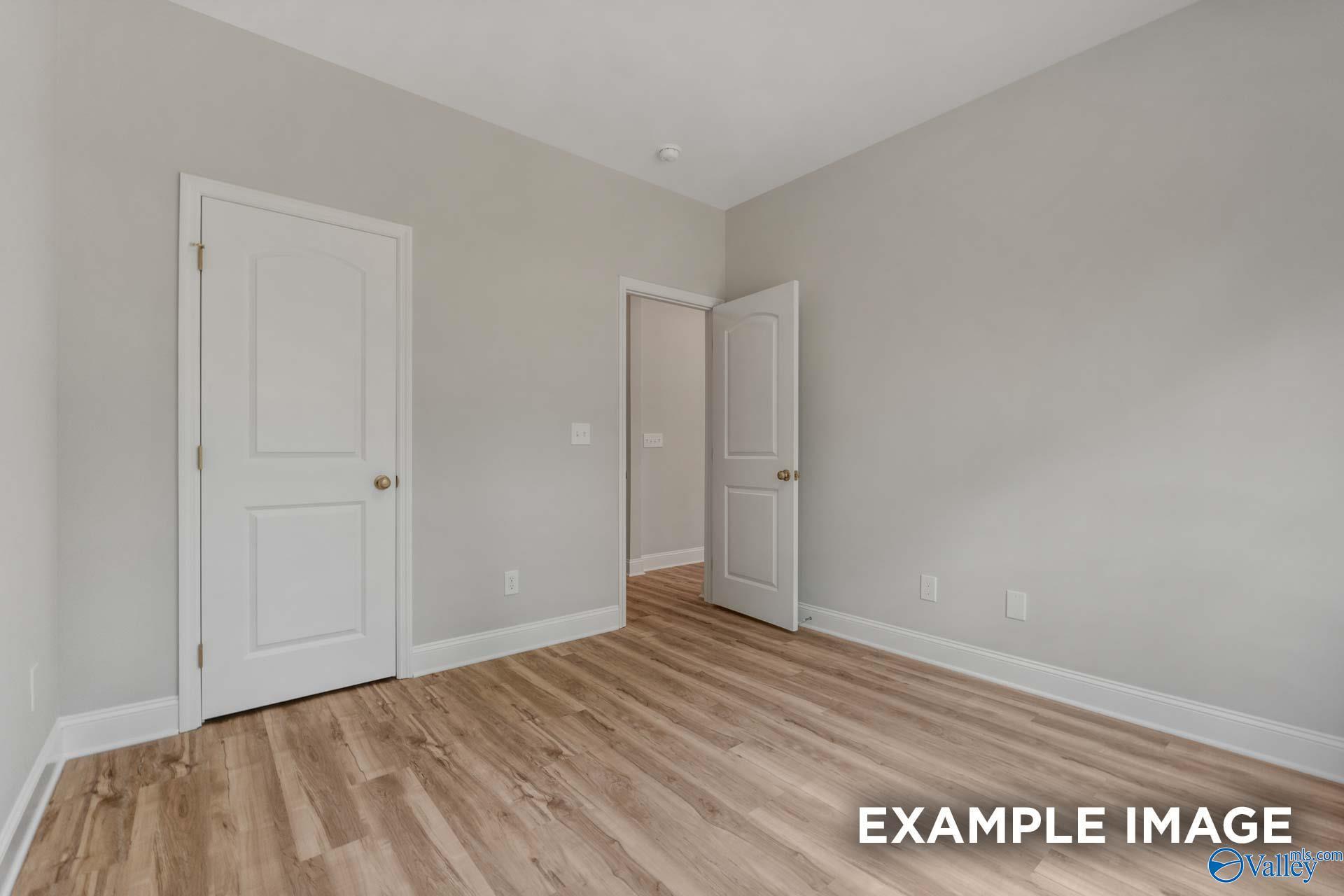 Cozy secondary bedroom featuring gray walls, white doors to bath, hardwood floors in Davidson Homes The Shelby C, Meridianville AL