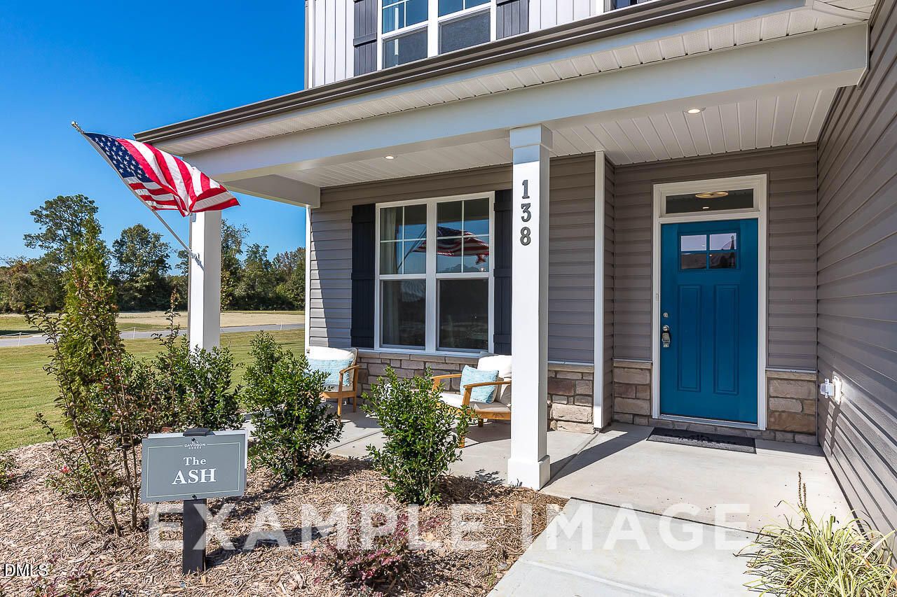 Front porch with blue door and American flag at The Ash C model home by Davidson Homes in Retreat at North Main, Lillington, NC