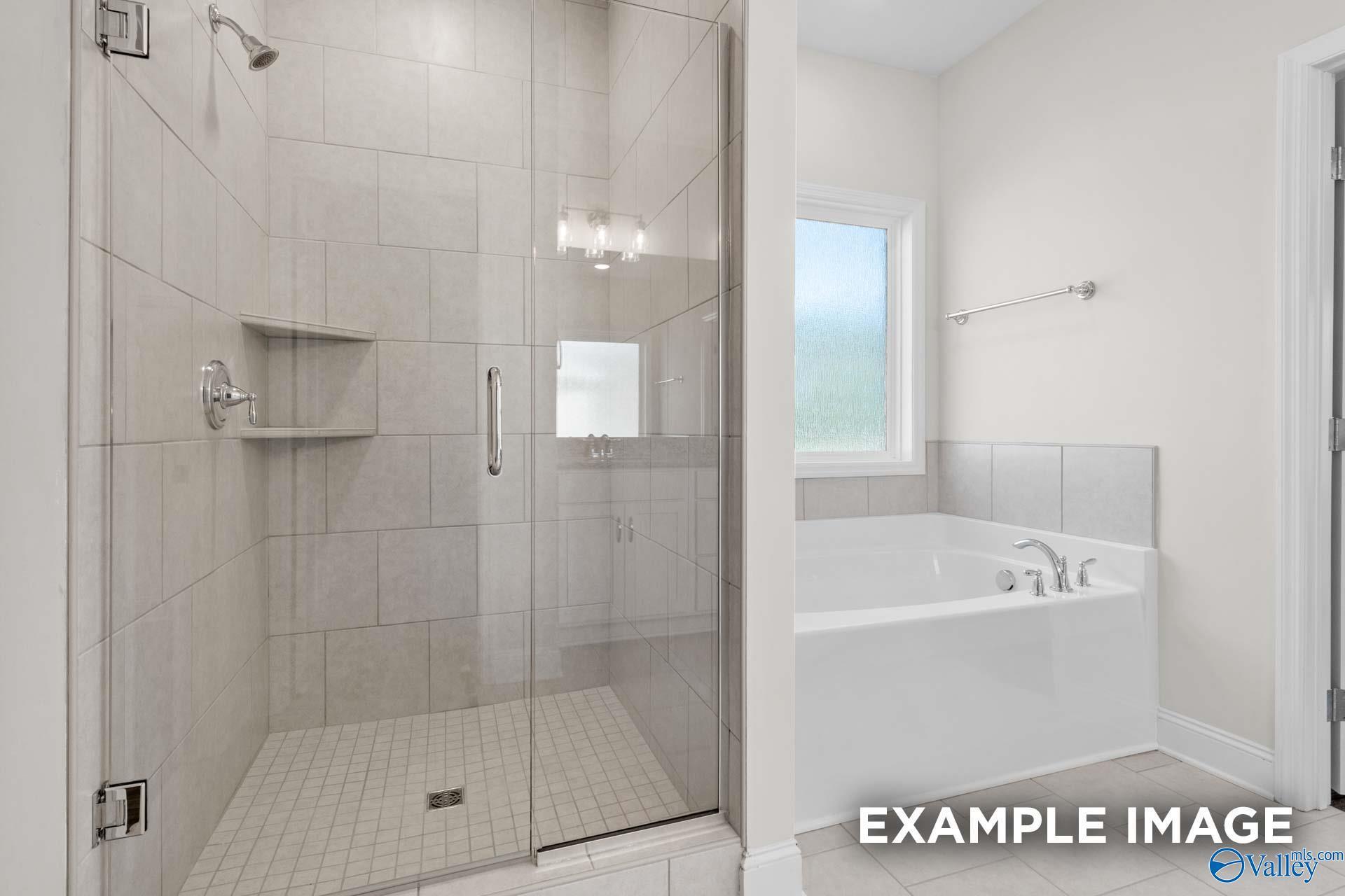 Modern master bath with frameless glass shower and deep soaking tub in Davidson Homes Montgomery C, Harvest AL