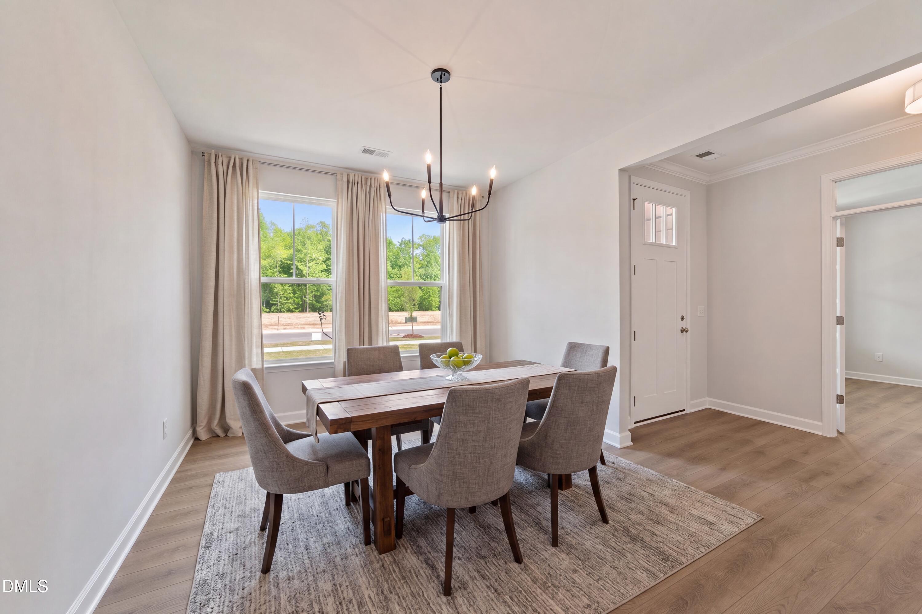 Bright dining room with modern chandelier and wood table in The Magnolia B floor plan at Wendell Ridge, North Carolina.