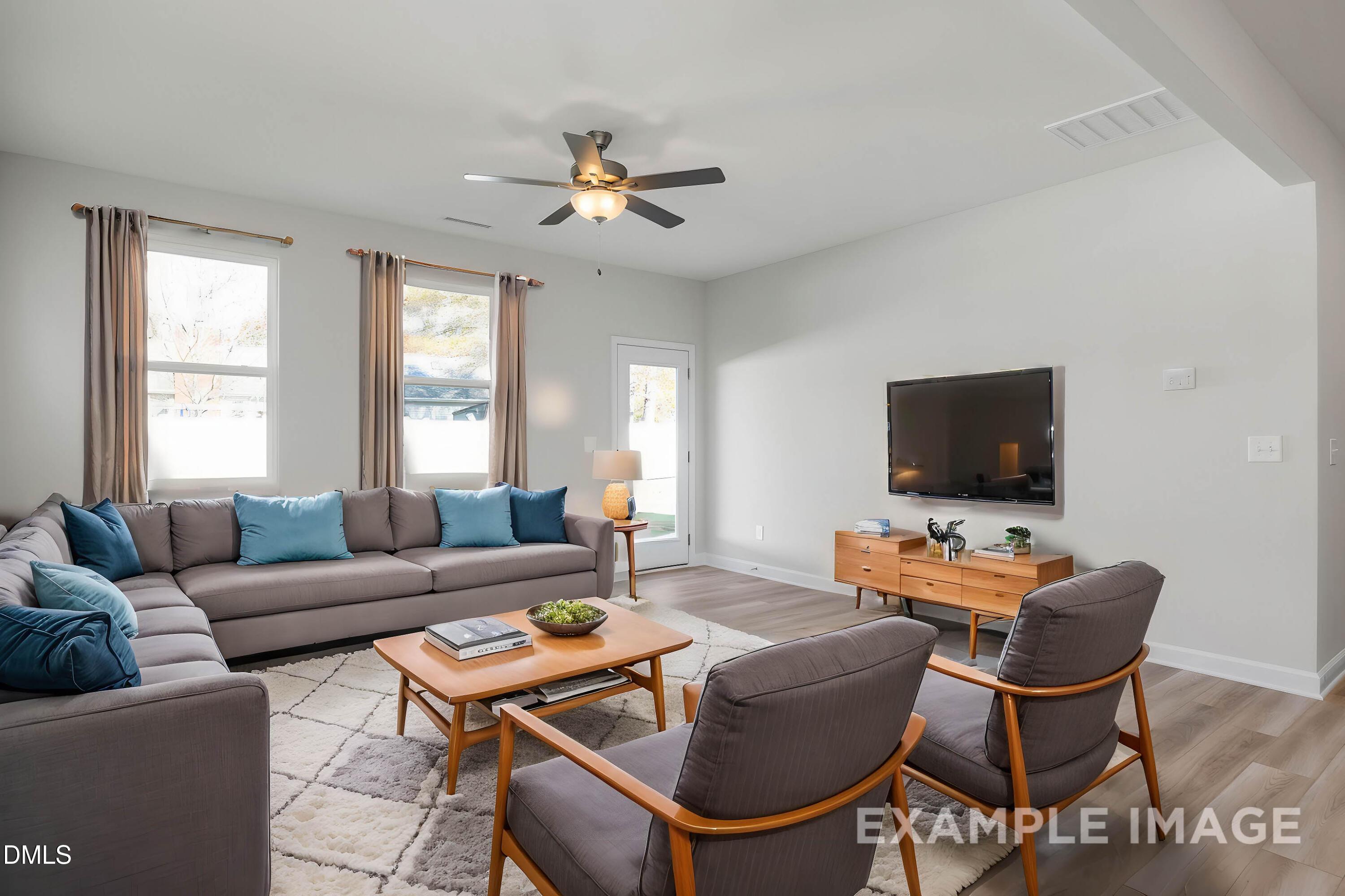 Inviting living room with L-shaped gray sofa, accent chairs, coffee table, ceiling fan in The Adalynn A 4-bedroom home by Davidson Homes, Gregory Village, Lillington, NC