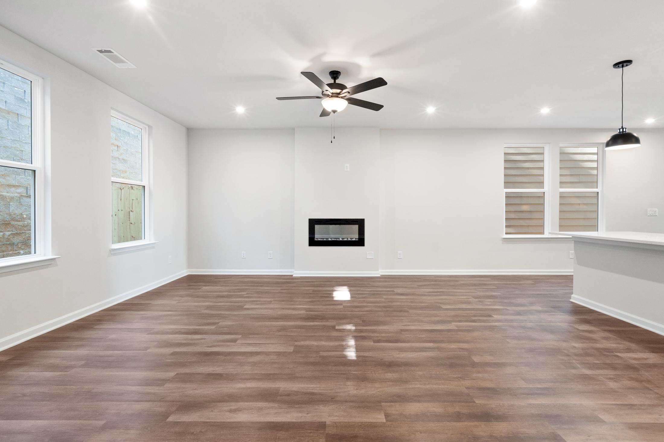 Spacious open-concept living room in The Cary B by Davidson Homes featuring modern fireplace, hardwood floors, and large windows