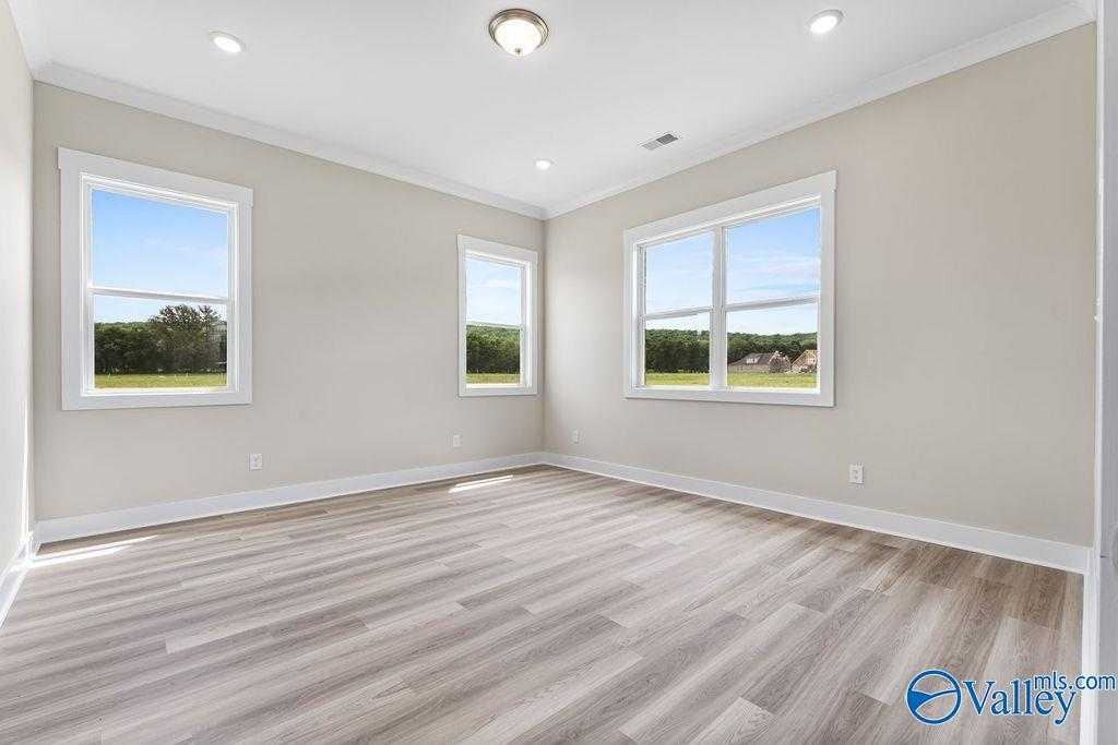 Bright bedroom with beige walls, hardwood floors, and large windows overlooking green fields in The Oxford 5-bedroom home, Owens Cross Roads