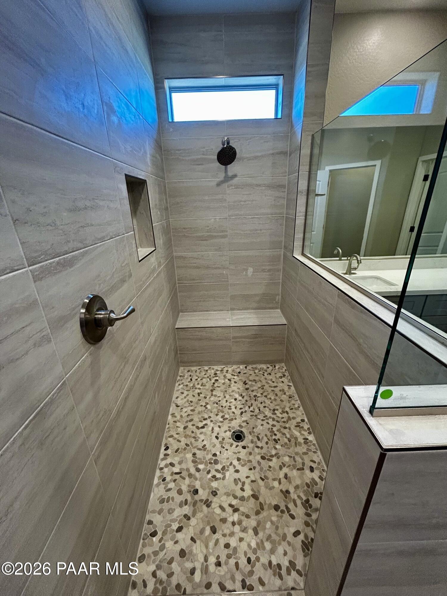 Walk-in tile shower with pebble floor and bench seat in The Harmony C floor plan at Pronghorn Ranch, Prescott Valley.