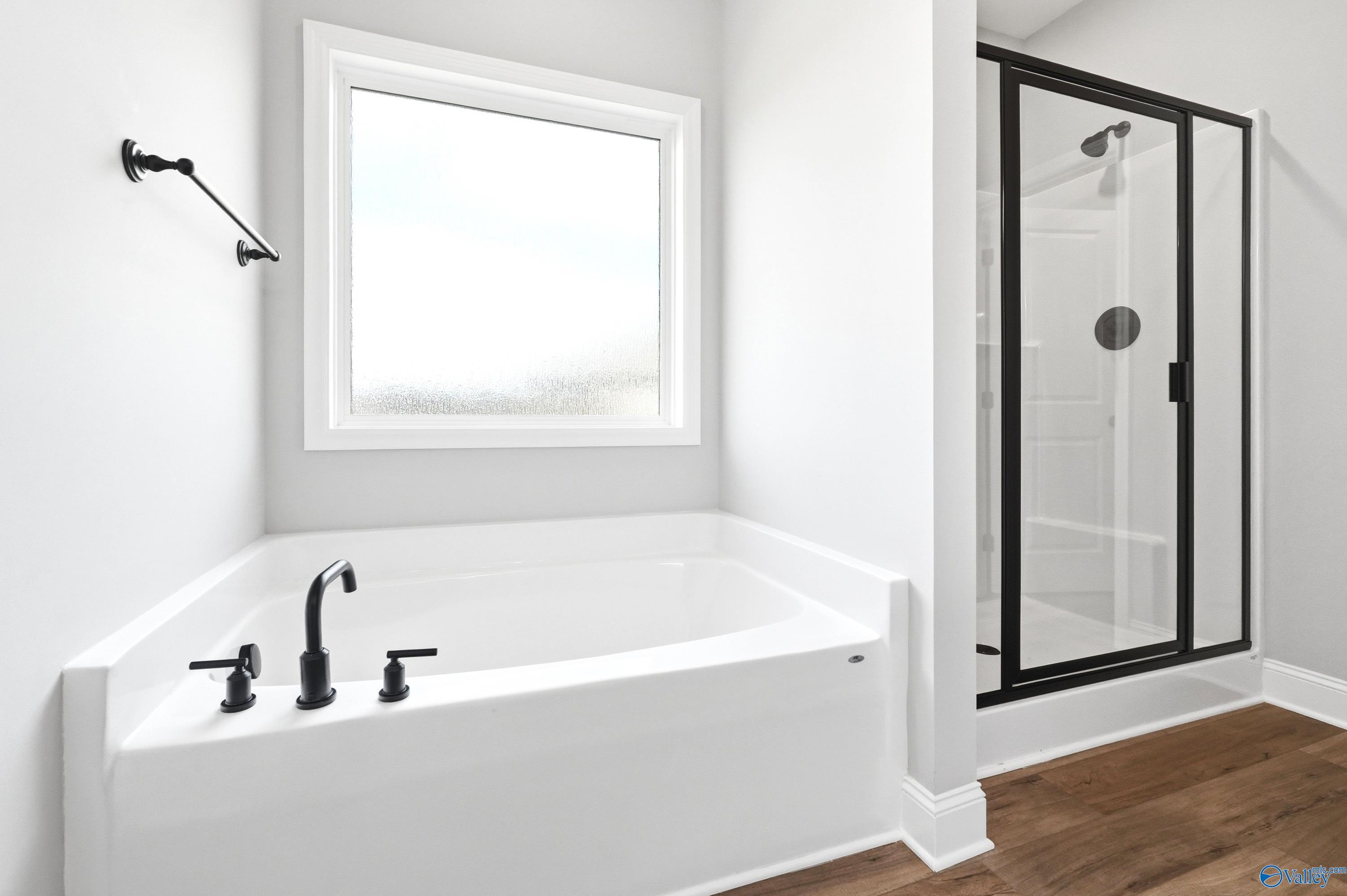 Modern primary bathroom with soaking tub and glass-enclosed shower in The Daphne D floor plan, Creekside, Harvest, AL.