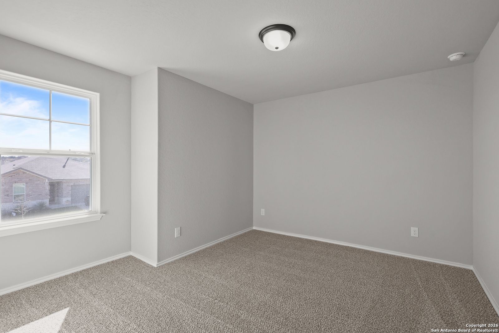Empty secondary bedroom with light gray walls, beige carpet, large window, and ceiling light in Davidson Homes Murray K, San Antonio