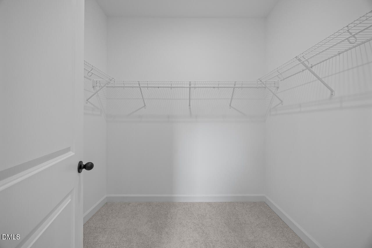 Spacious walk-in closet with wire shelving and carpet in Davidson Homes The Ashport M, Wendell Ridge, Wendell, North Carolina
