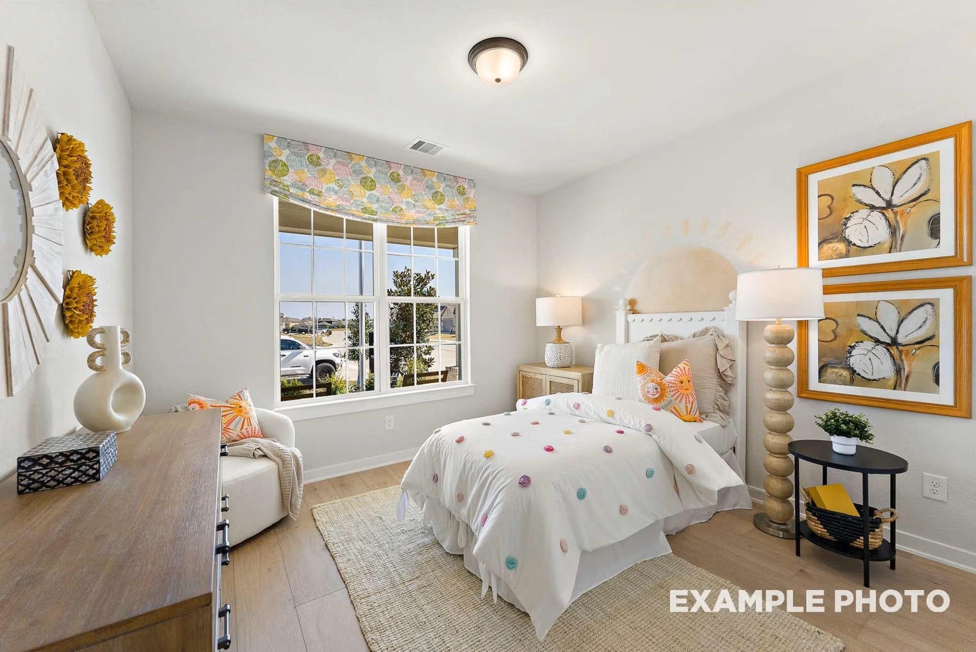 Cozy child's bedroom with colorful polka-dot bedding, sunburst mirror, and window view in Davidson Homes The Everett C, Dayton, Texas