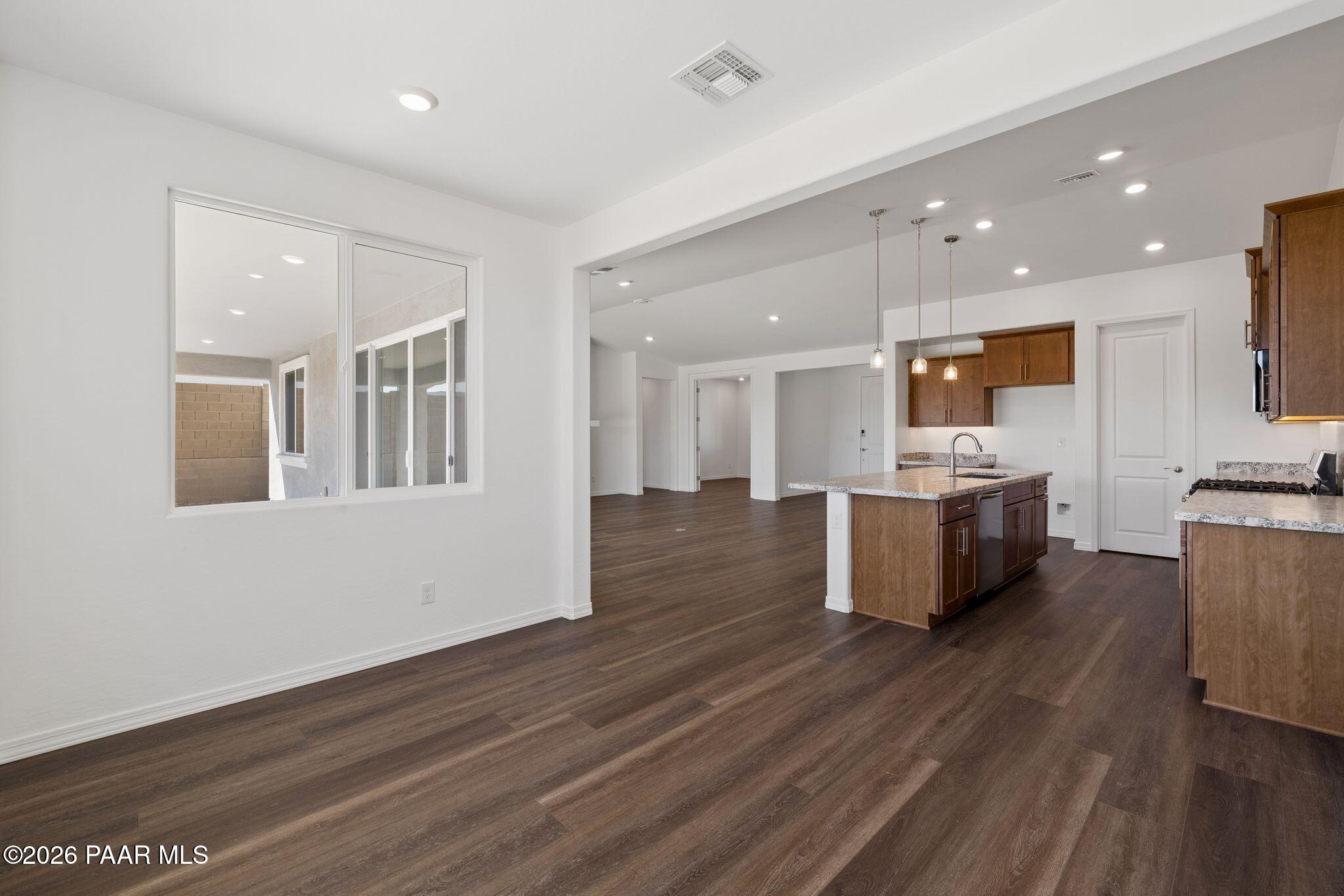 Open-concept kitchen with warm wood cabinets, quartz island, and pendant lights in Davidson Homes The Monarch A, Prescott, Arizona