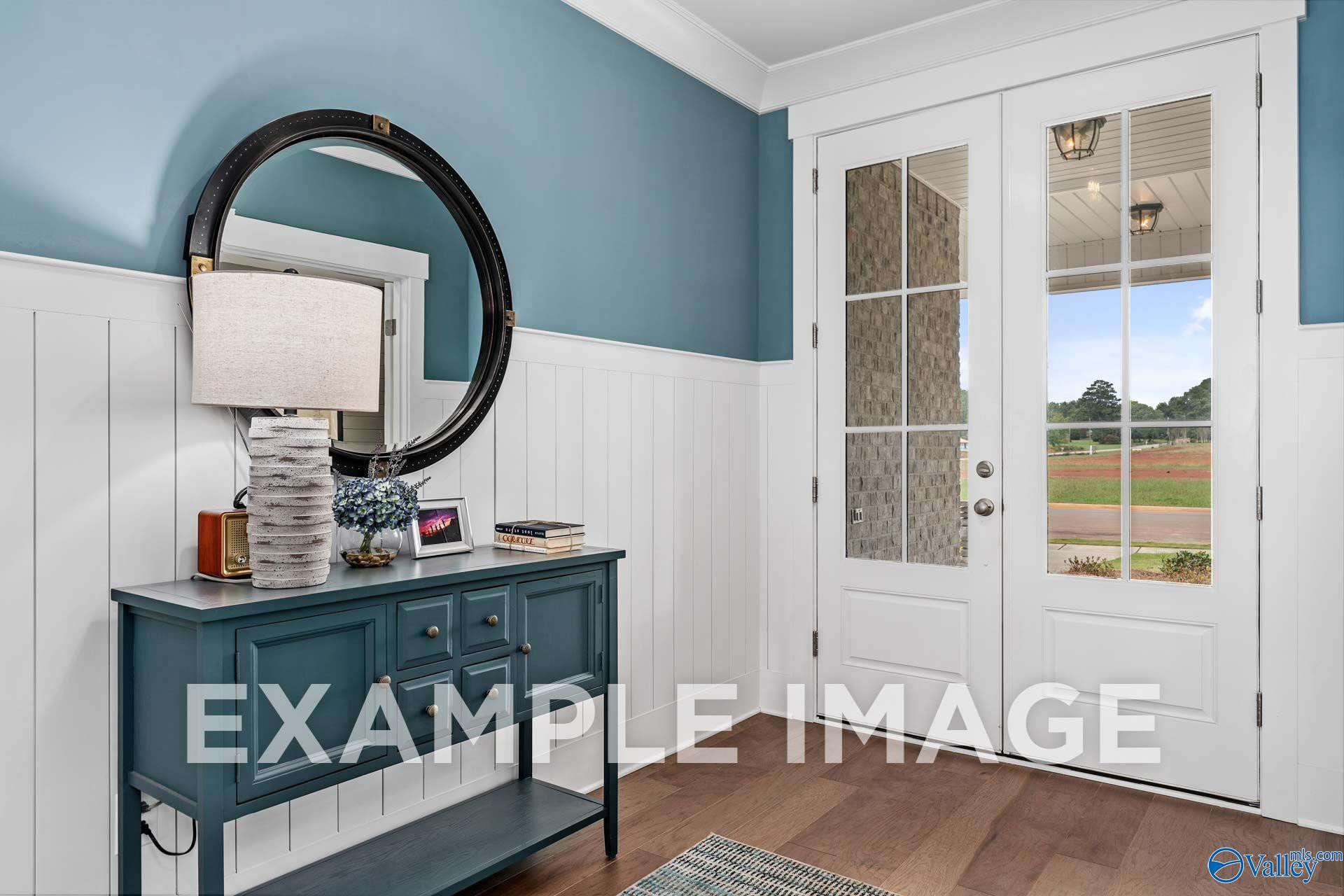 Welcoming foyer with board-and-batten wainscoting, glass-panel French doors, and console table in Davidson Homes' The Harrison, Hartselle