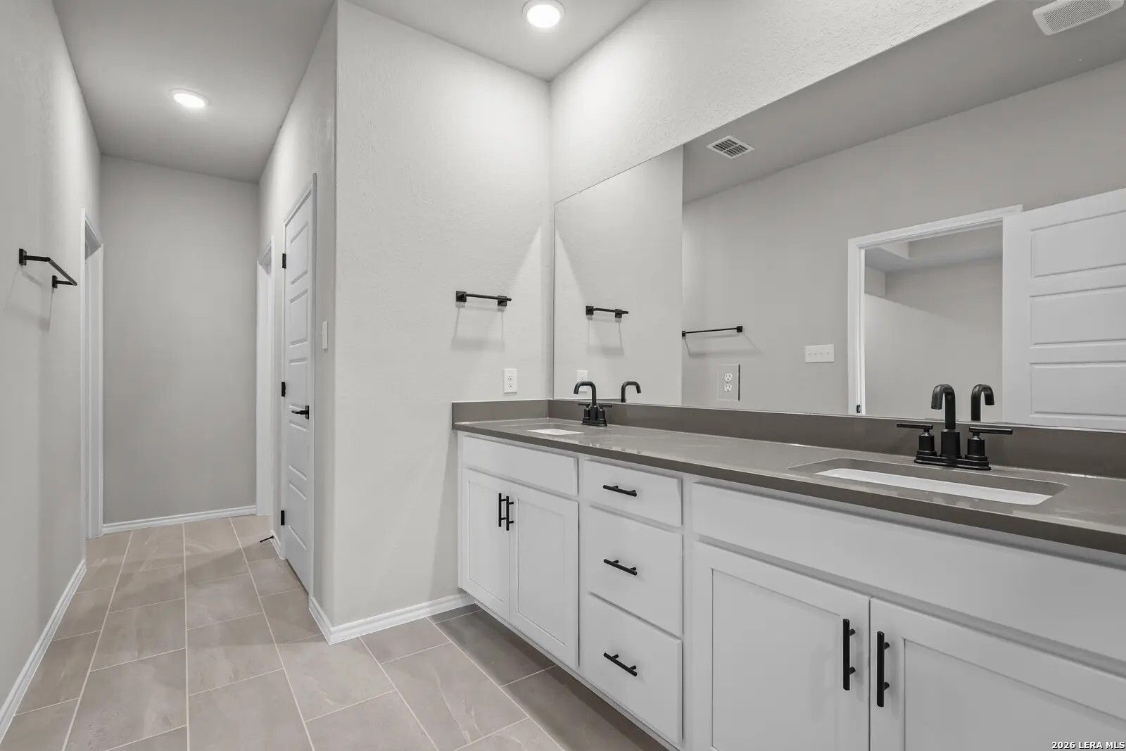 Modern bathroom with double vanity, white cabinets, and matte black fixtures in The Glenwood E by Davidson Homes.