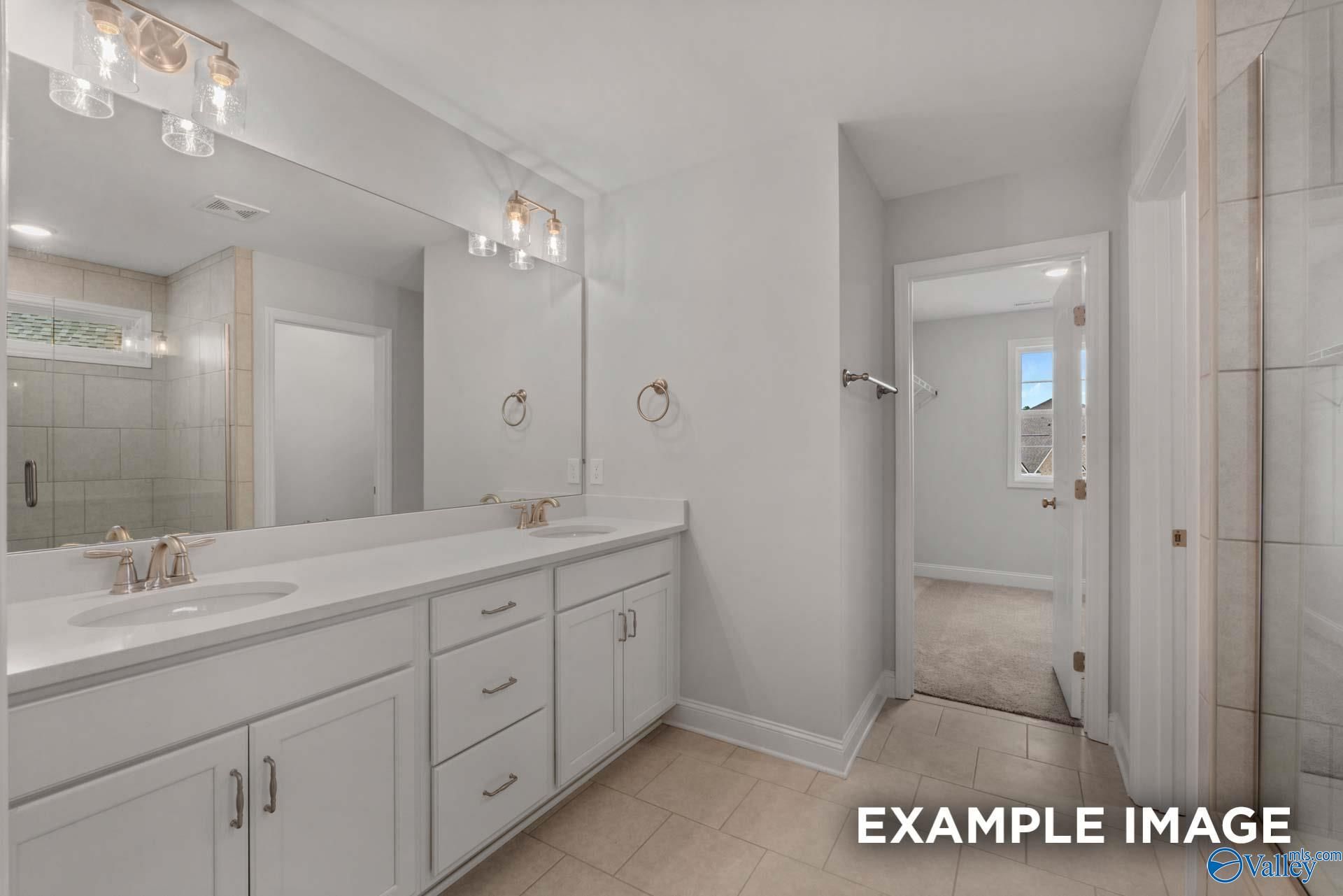 Modern master bathroom with double vanity, white shaker cabinets, gold faucets, and tiled glass shower in Davidson Homes Shelby C, Arab, Alabama