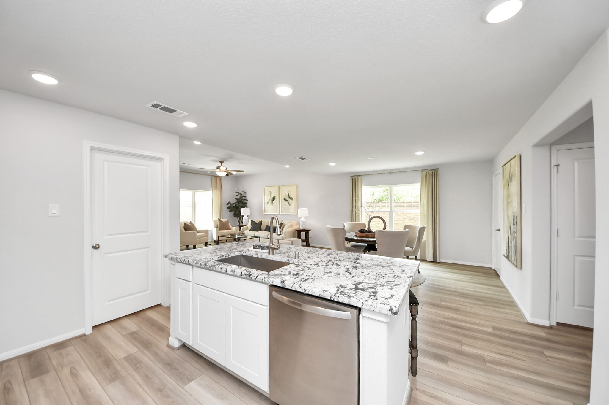 Open-concept kitchen and living area at Sunterra in Katy, Texas by Davidson Homes with granite island and light flooring.