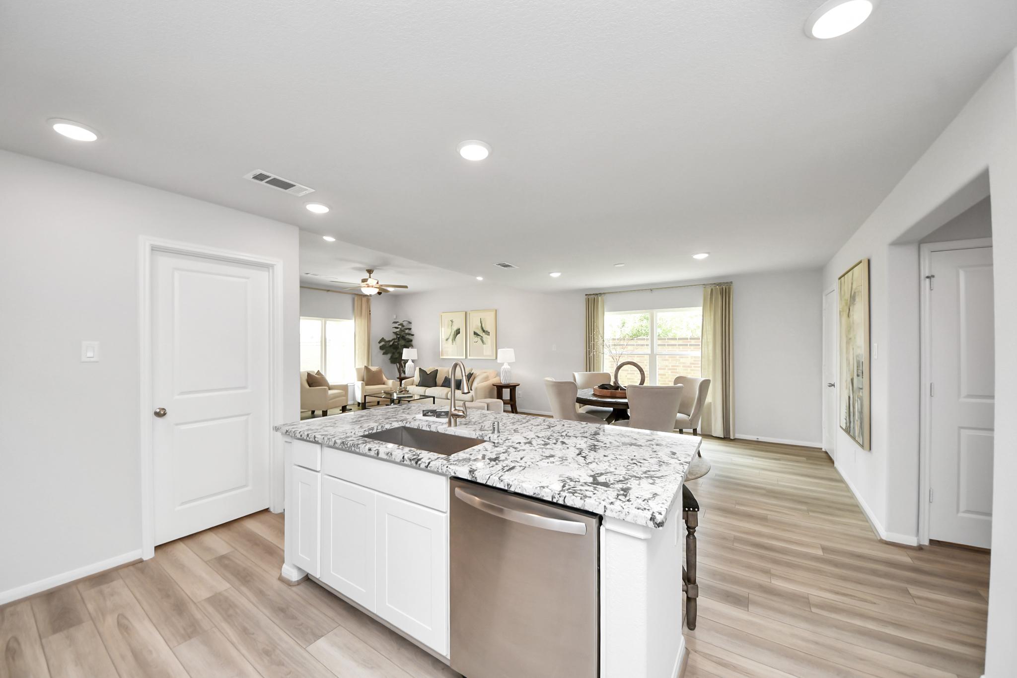 Open-concept kitchen and living area at Sunterra in Katy, Texas by Davidson Homes with granite island and light flooring.