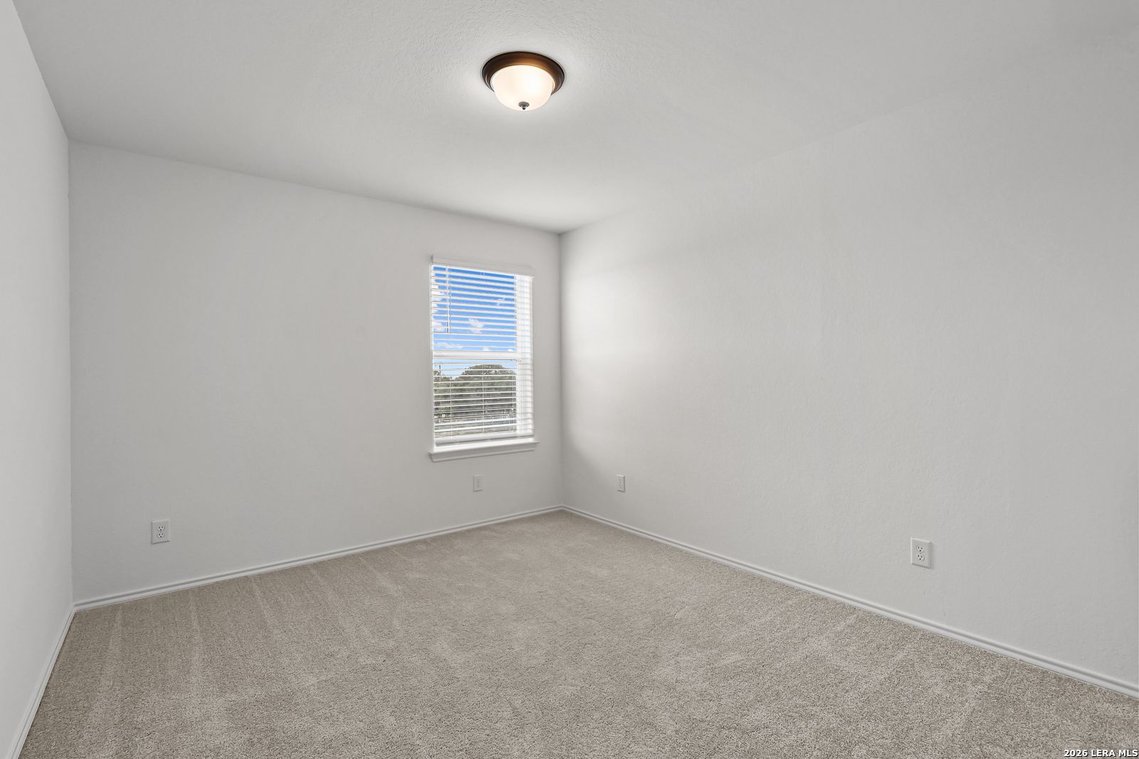 Bright, carpeted bedroom with neutral walls in The Gillian C floor plan at Meadows at Oak Creek, San Antonio, Texas.