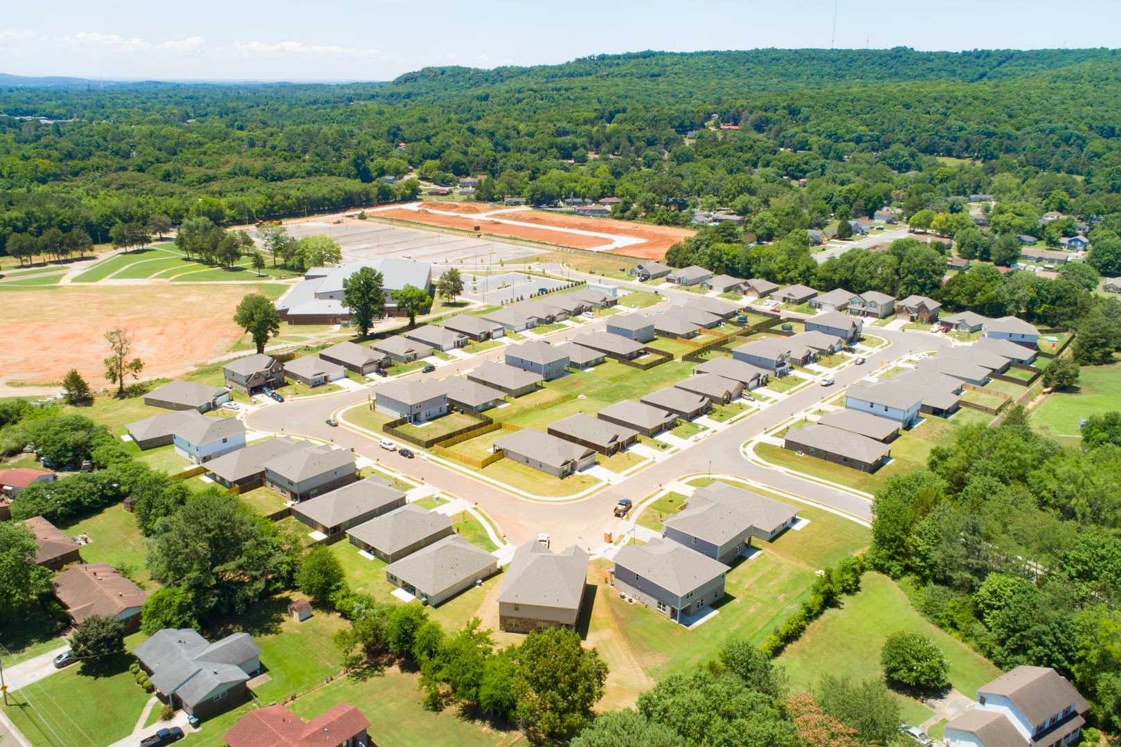 Aerial view of Jaguar Hills neighborhood in Huntsville Alabama featuring new single-family homes, green lawns, and surrounding forests