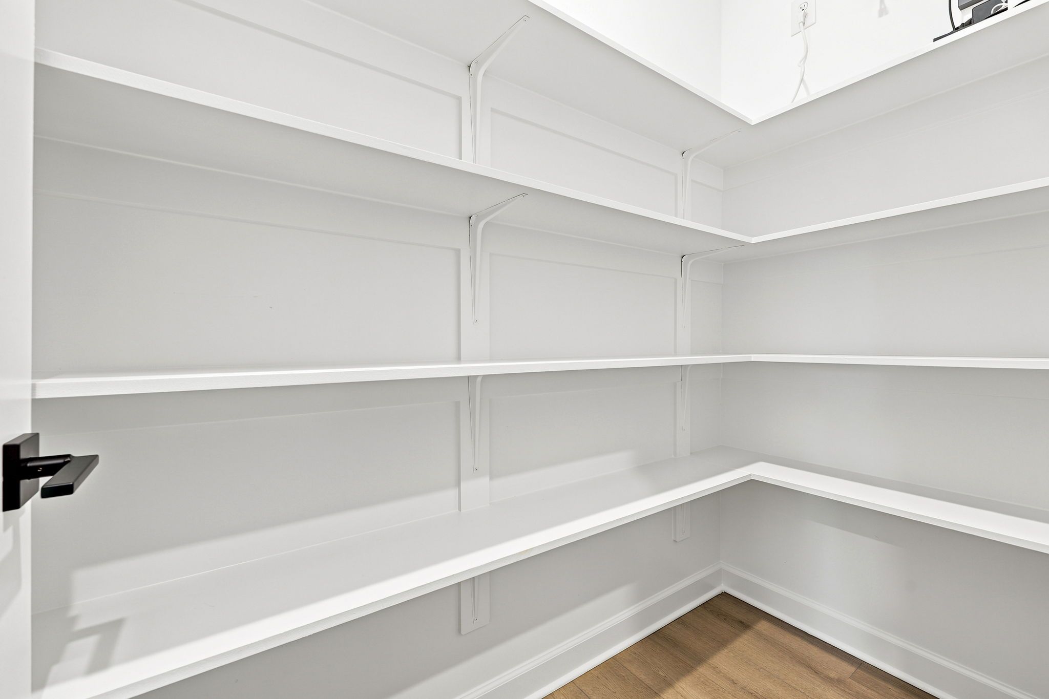 Spacious walk-in pantry with white custom shelving at Montrose in Aberdeen, NC by Davidson Homes.