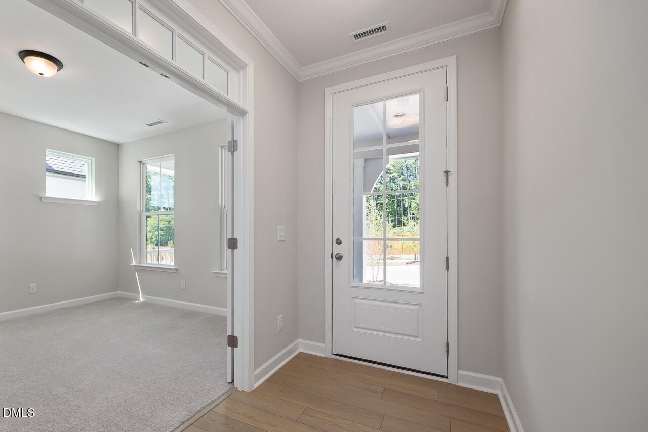 Bright foyer with glass-paneled front door and adjacent home office in The Ashport L at Sage on North Main, Wake Forest.