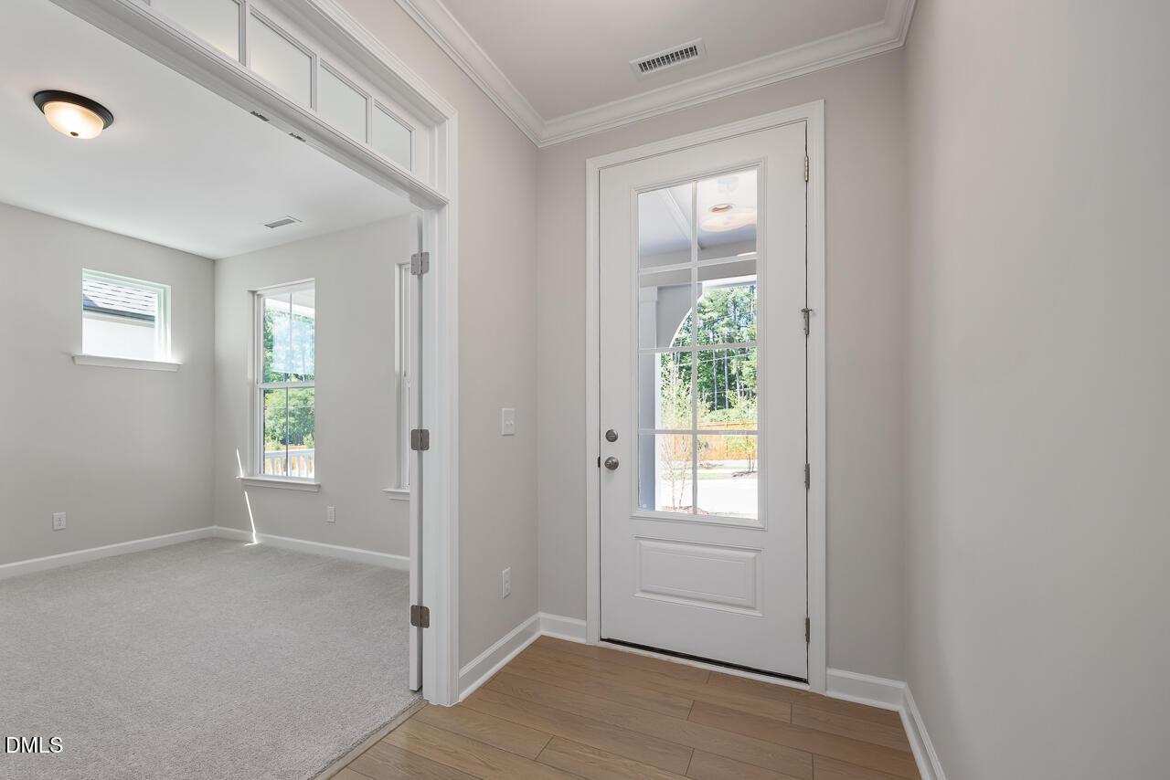 Bright foyer with glass-paneled front door and adjacent home office in The Ashport L at Sage on North Main, Wake Forest.