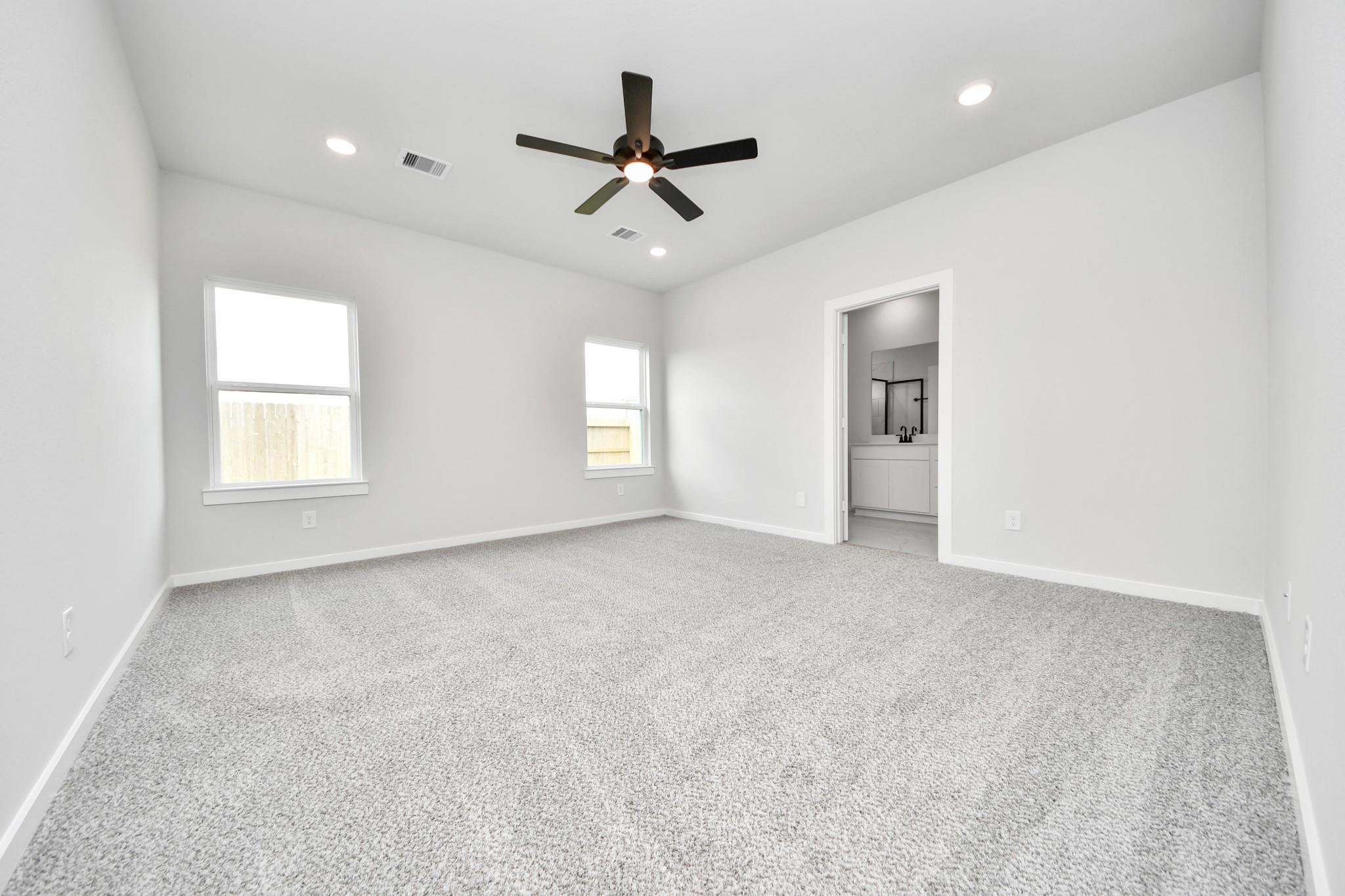Spacious, carpeted bedroom with ceiling fan and en-suite bathroom in The Sorrento E floor plan at Sundance Cove, Crosby.