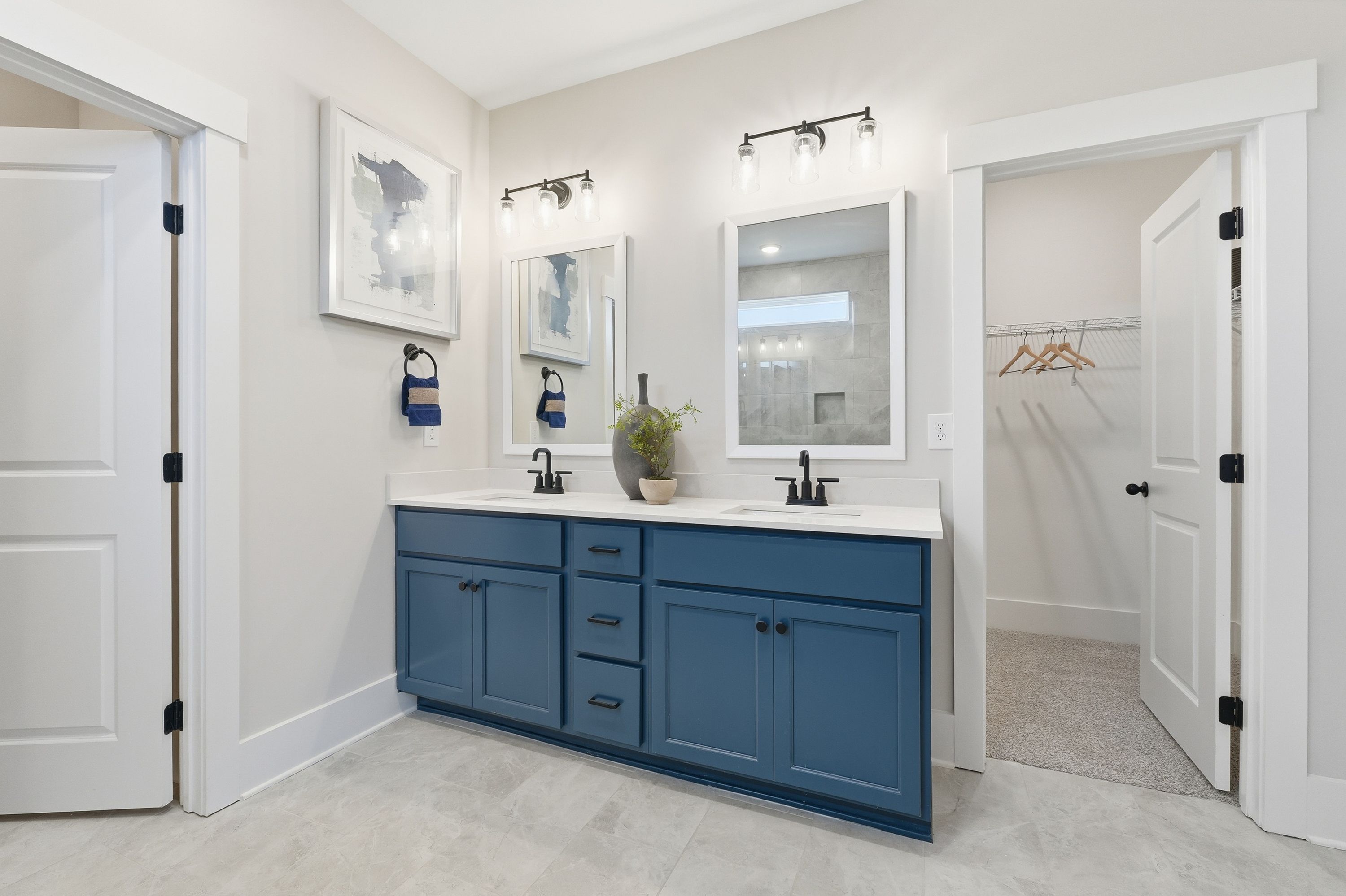 Spacious master bathroom at Noble Ridge in Cullman Alabama with navy blue double vanity mirrors and walk-in closet