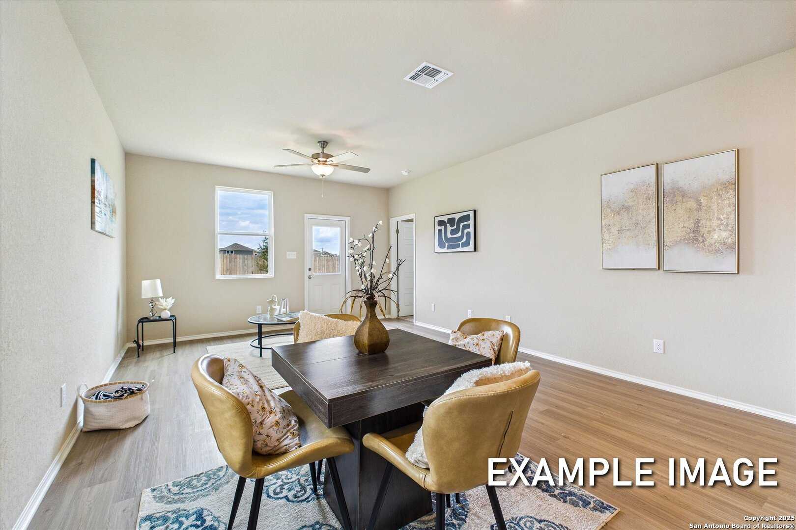 Elegant dining room with wooden table, upholstered chairs, and abstract wall art in The Comal B by Davidson Homes, Agave, San Antonio