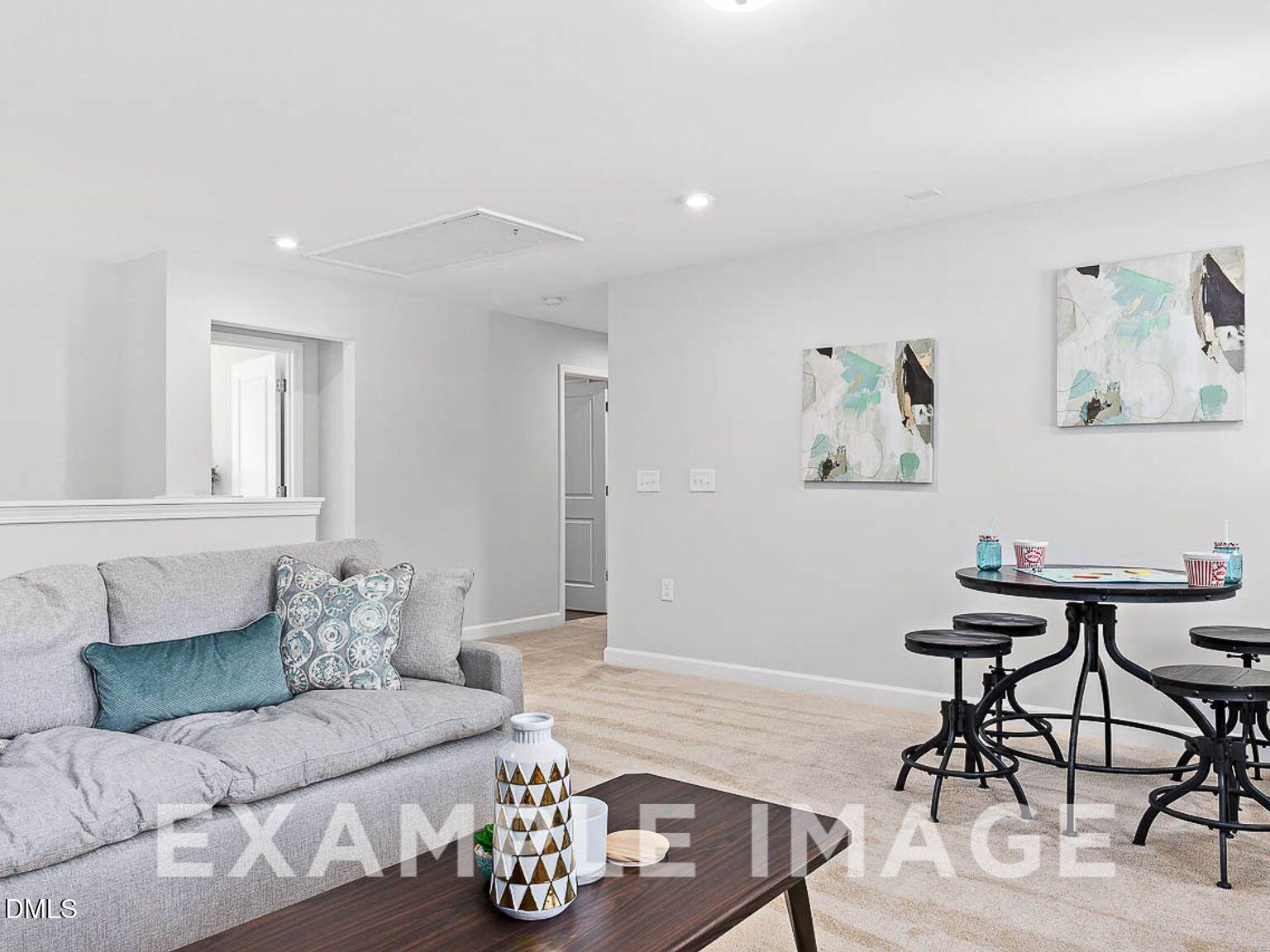 Cozy living room with gray sofa, blue pillows, round black bistro table, and abstract art in Davidson Homes Chestnut B, Lillington, NC