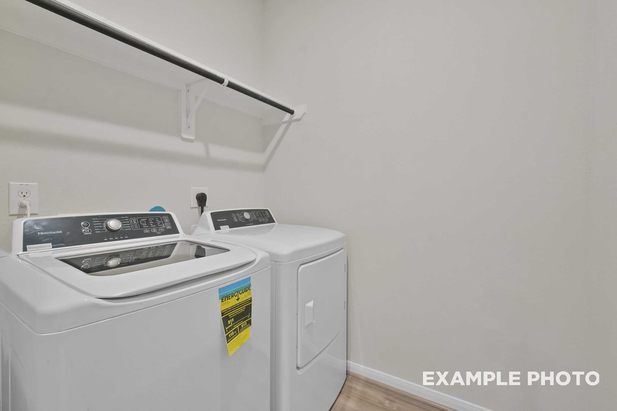 Spacious laundry room in The Comal Davidson Homes plan featuring side-by-side white washer dryer and built-in shelves