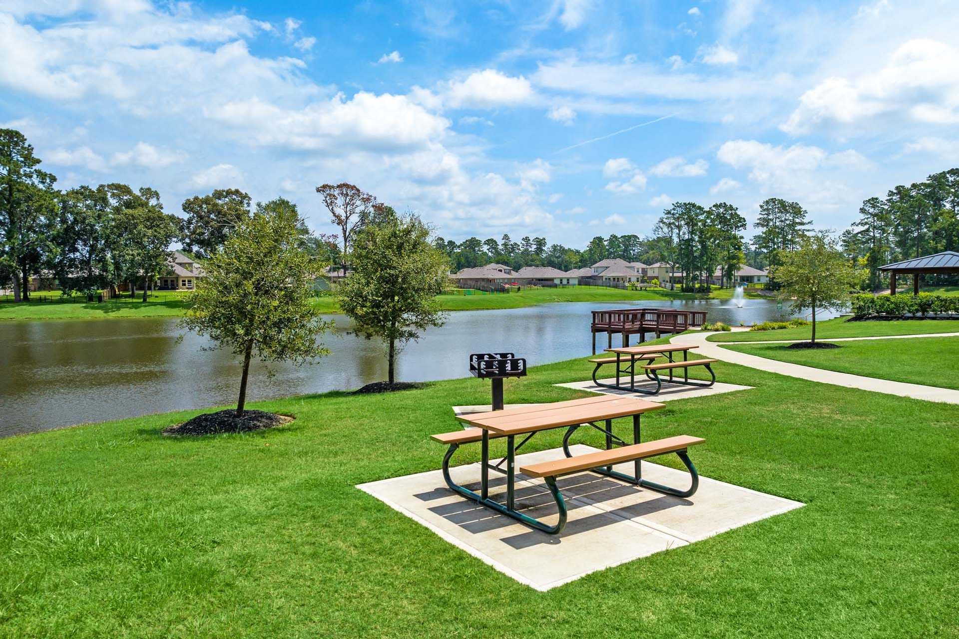 Lakeside picnic area at Lakes at Black Oak in Magnolia TX with wooden tables barbecue grill pavilion and oak trees