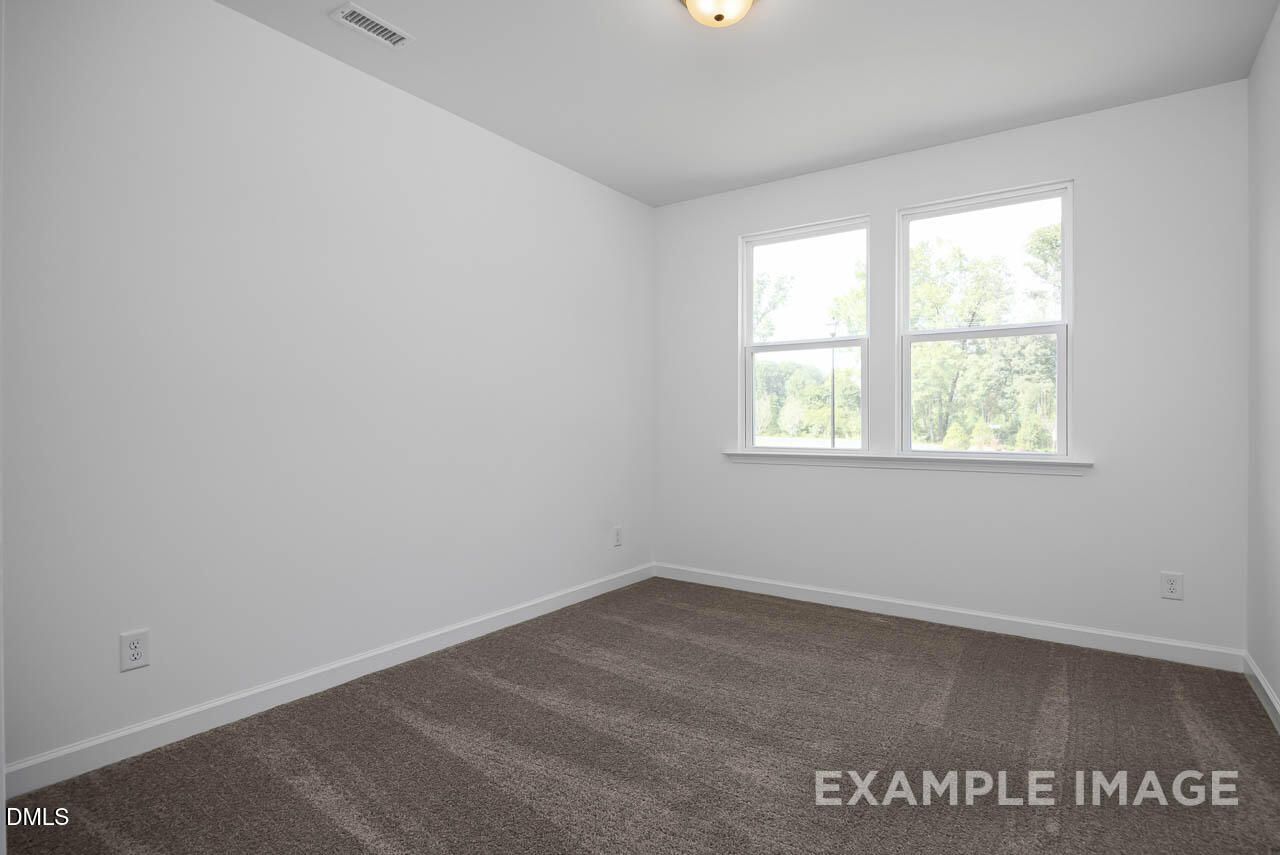 Bright secondary bedroom with white walls, large double windows, and plush carpet in The Willow D 4-bedroom home, Zebulon, NC