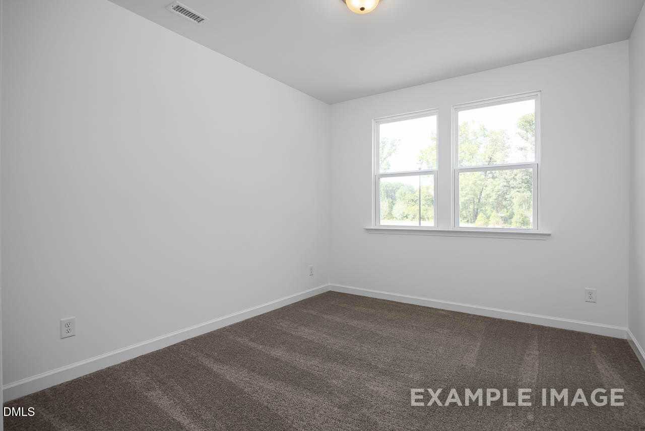 Bright secondary bedroom with white walls, large double windows, and plush carpet in The Willow D 4-bedroom home, Zebulon, NC
