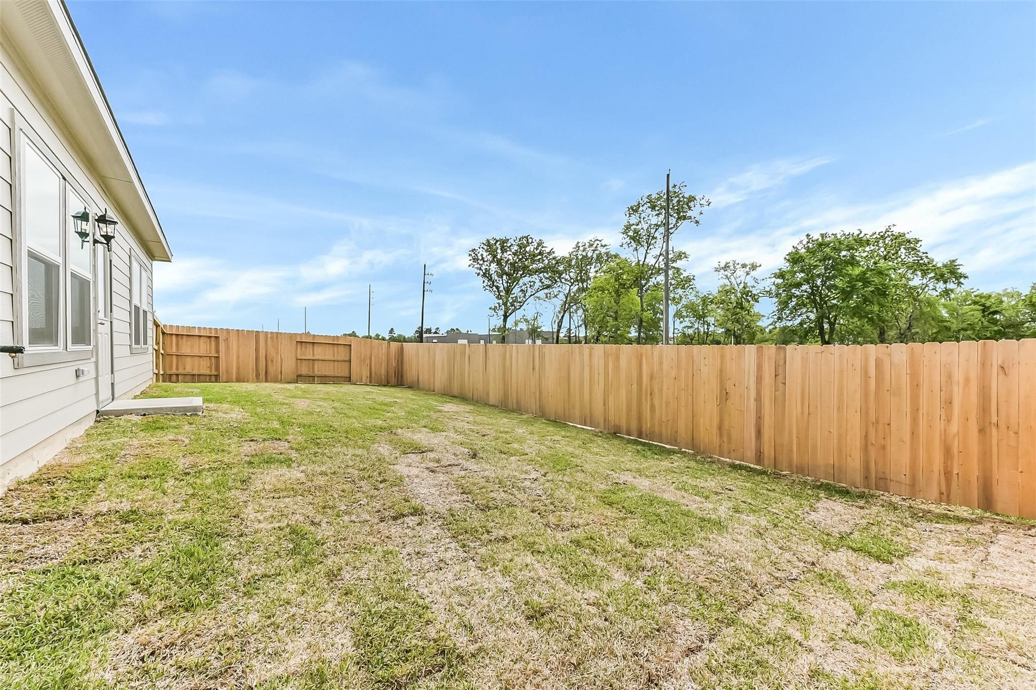 Private backyard with wooden privacy fence and grassy lawn beside Davidson Homes The Frio G in Magnolia, Texas