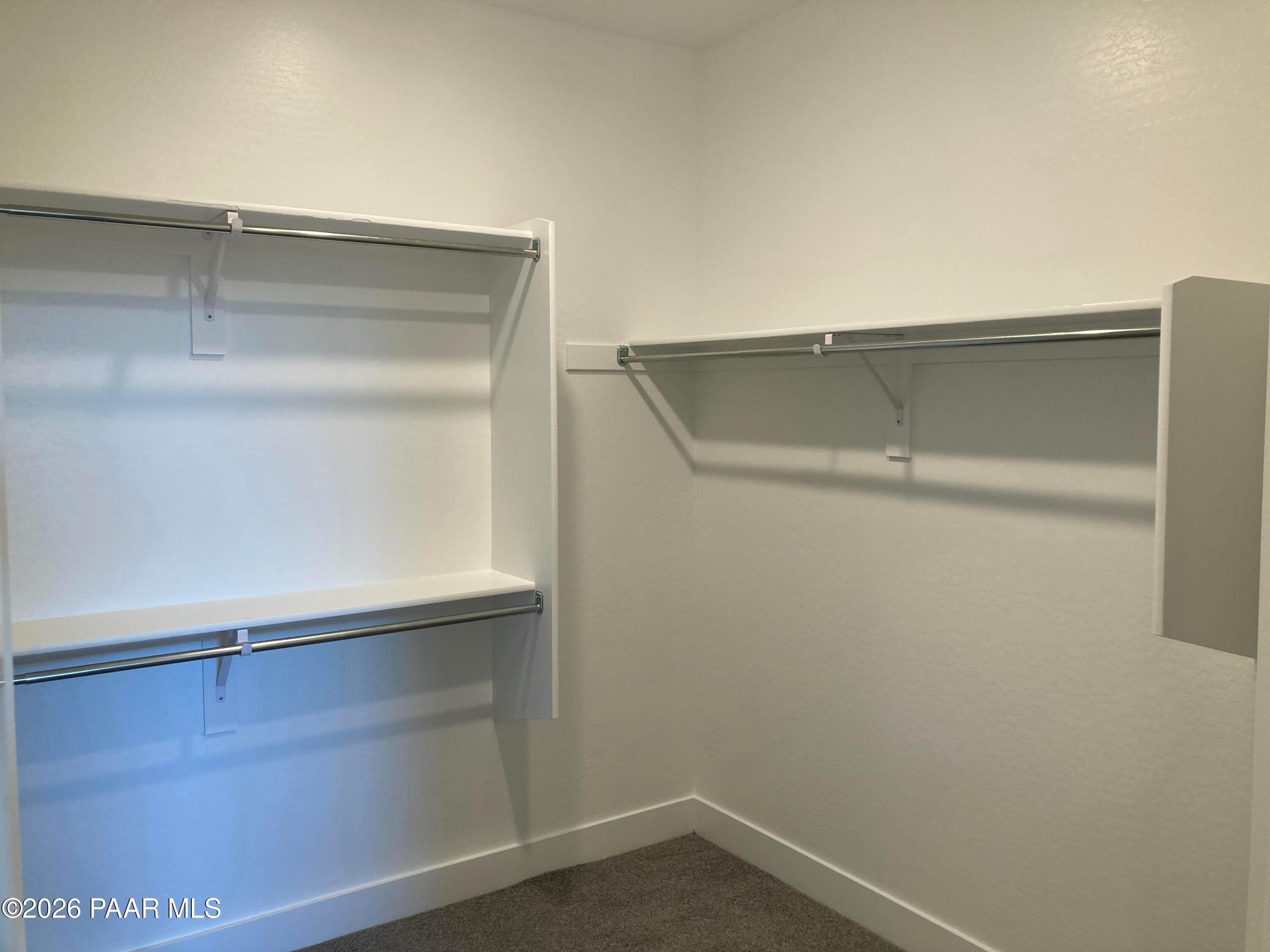 Spacious walk-in closet with built-in shelves and hanging rods in Davidson Homes The Malibu C, Prescott, Arizona