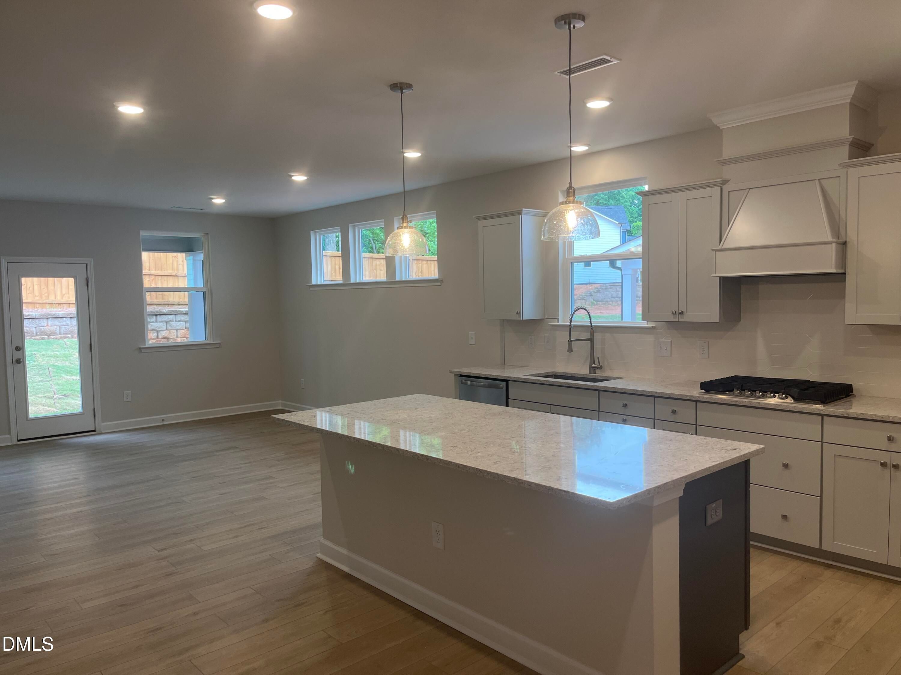 Open-concept kitchen with white cabinets, quartz island, gas range, and pendant lights in Davidson Homes Ashport G, Wake Forest NC