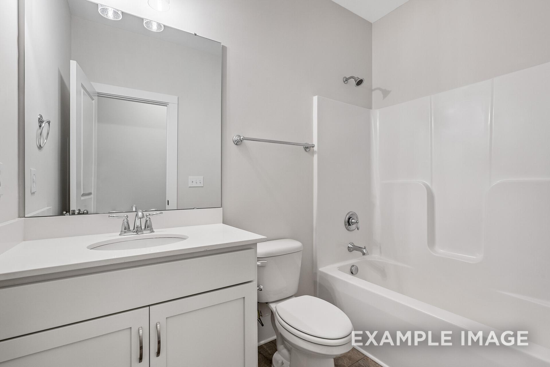 Bright secondary bathroom in The Rockford featuring white vanity, large mirror, bathtub shower combo, and modern fixtures
