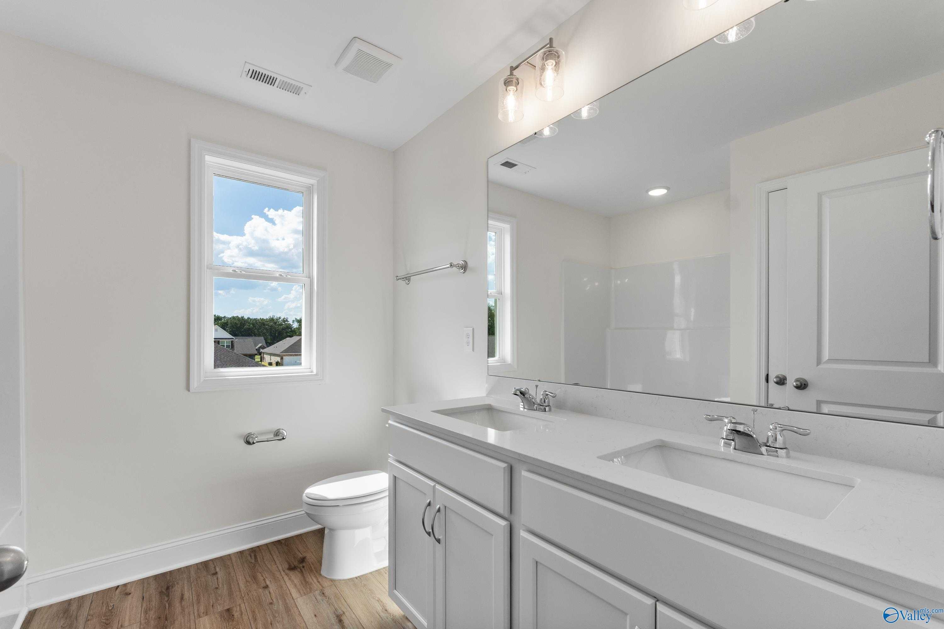 Modern master bathroom featuring double vanity, quartz countertop, large mirror, and natural light in Davidson Homes The Shelby A, New Market, AL