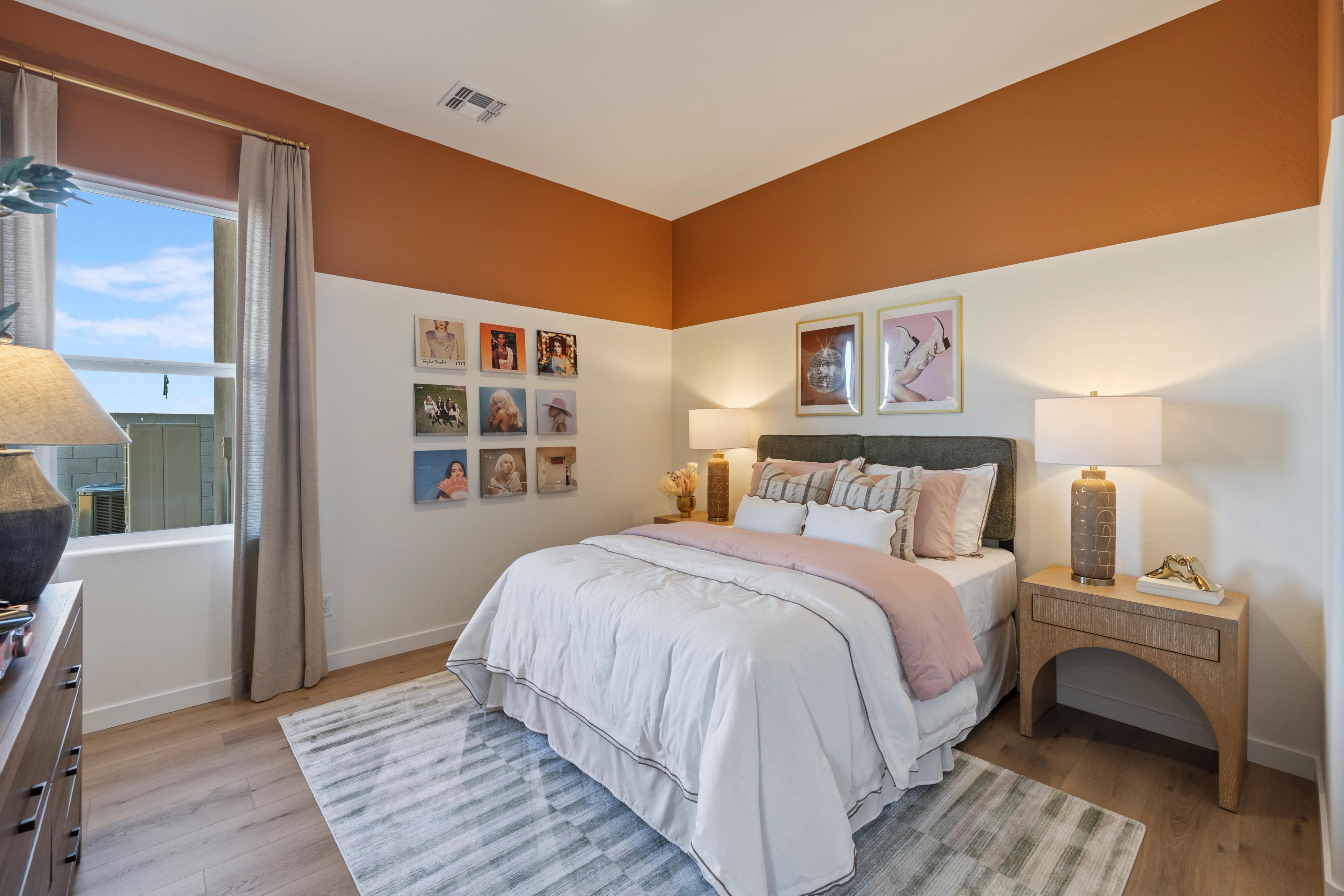 Cozy bedroom with queen bed, orange accent walls, framed photos, lamps, and hardwood floors at Hidden Hills in Prescott, Arizona