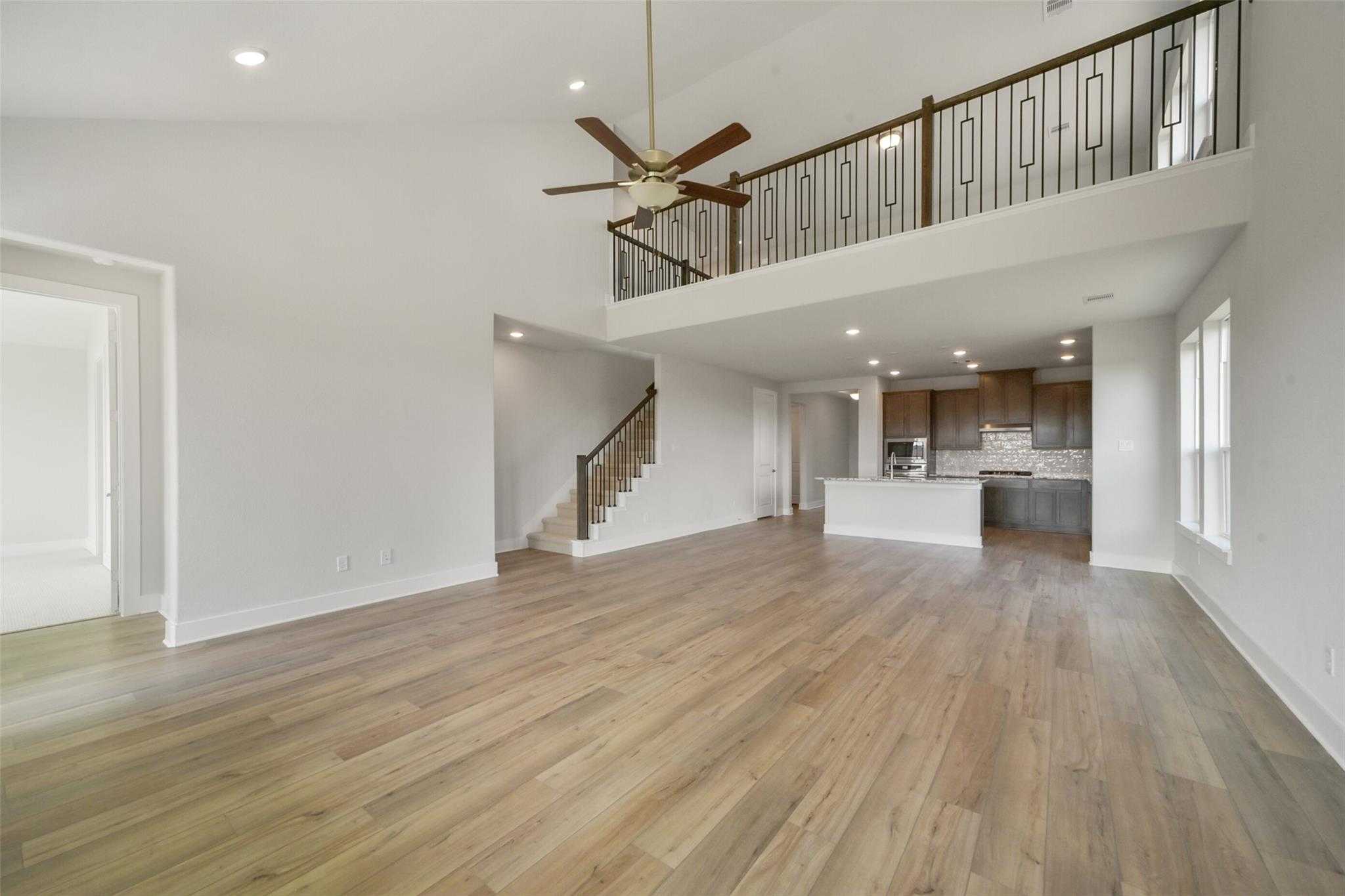 Expansive two-story open living area with hardwood floors, staircase, and balcony overlooking kitchen in The Zion A by Davidson Homes, Lago Mar, Texas City