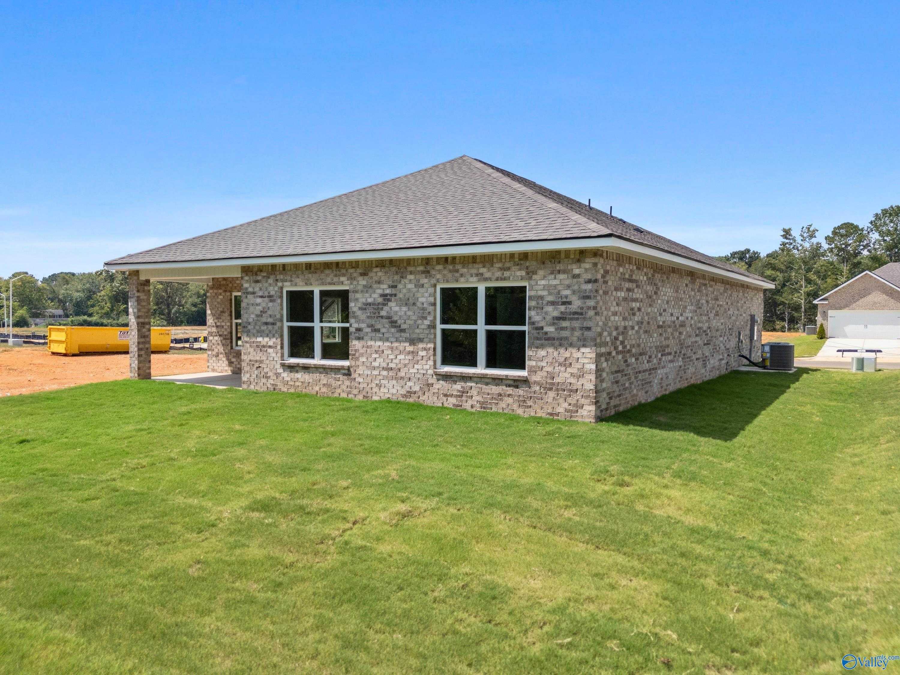 Side view of brick ranch-style The Franklin home with covered porch, double windows, and lush green lawn in Spragins Cove, Huntsville, Alabama