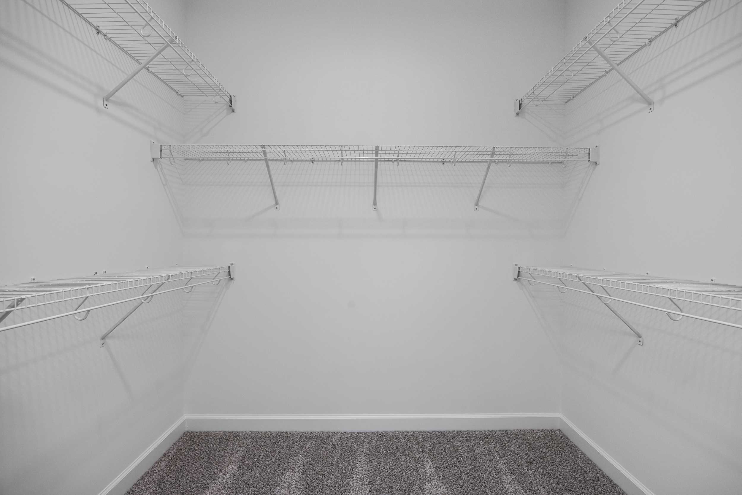 Spacious walk-in closet in The Magnolia A with white wire shelving on three walls and carpeted floor