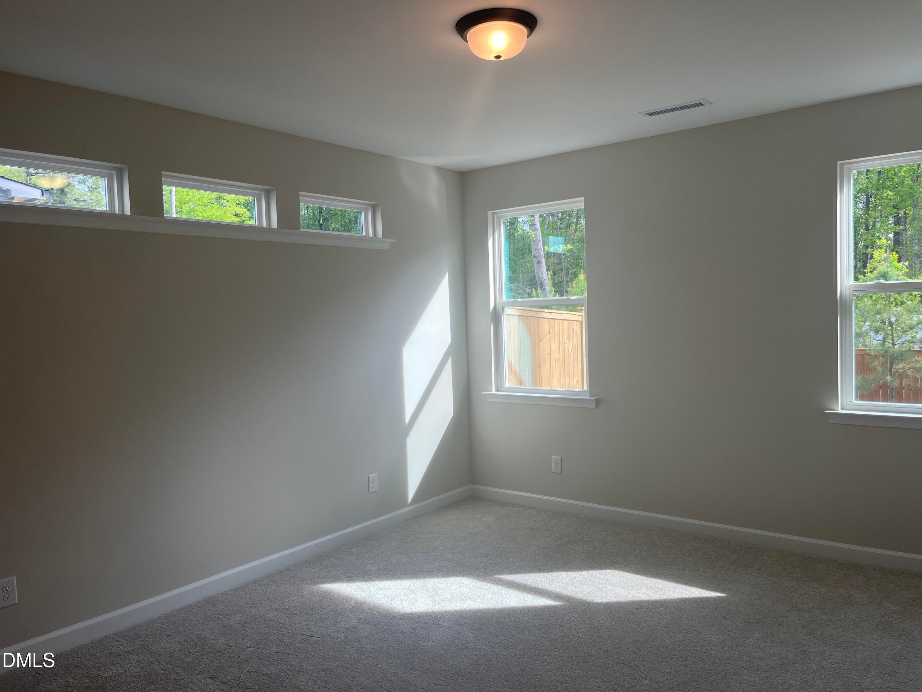 Bright bedroom with clerestory windows, wooded view, beige carpet, and sunlight in Davidson Homes Ashport L, Wake Forest, NC