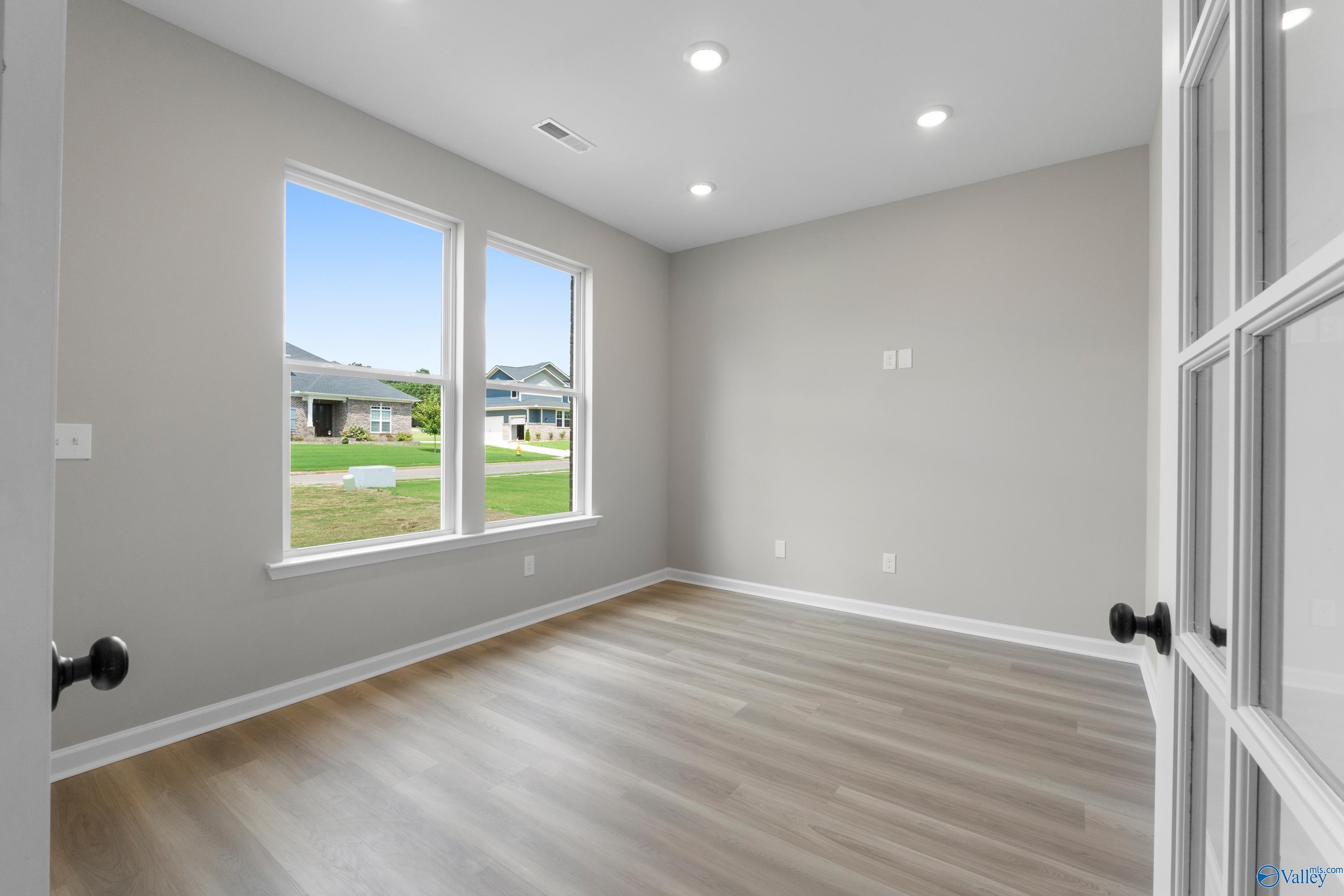 Bright secondary bedroom with large windows, light gray walls, and laminate flooring in Davidson Homes Dorado, Huntsville AL