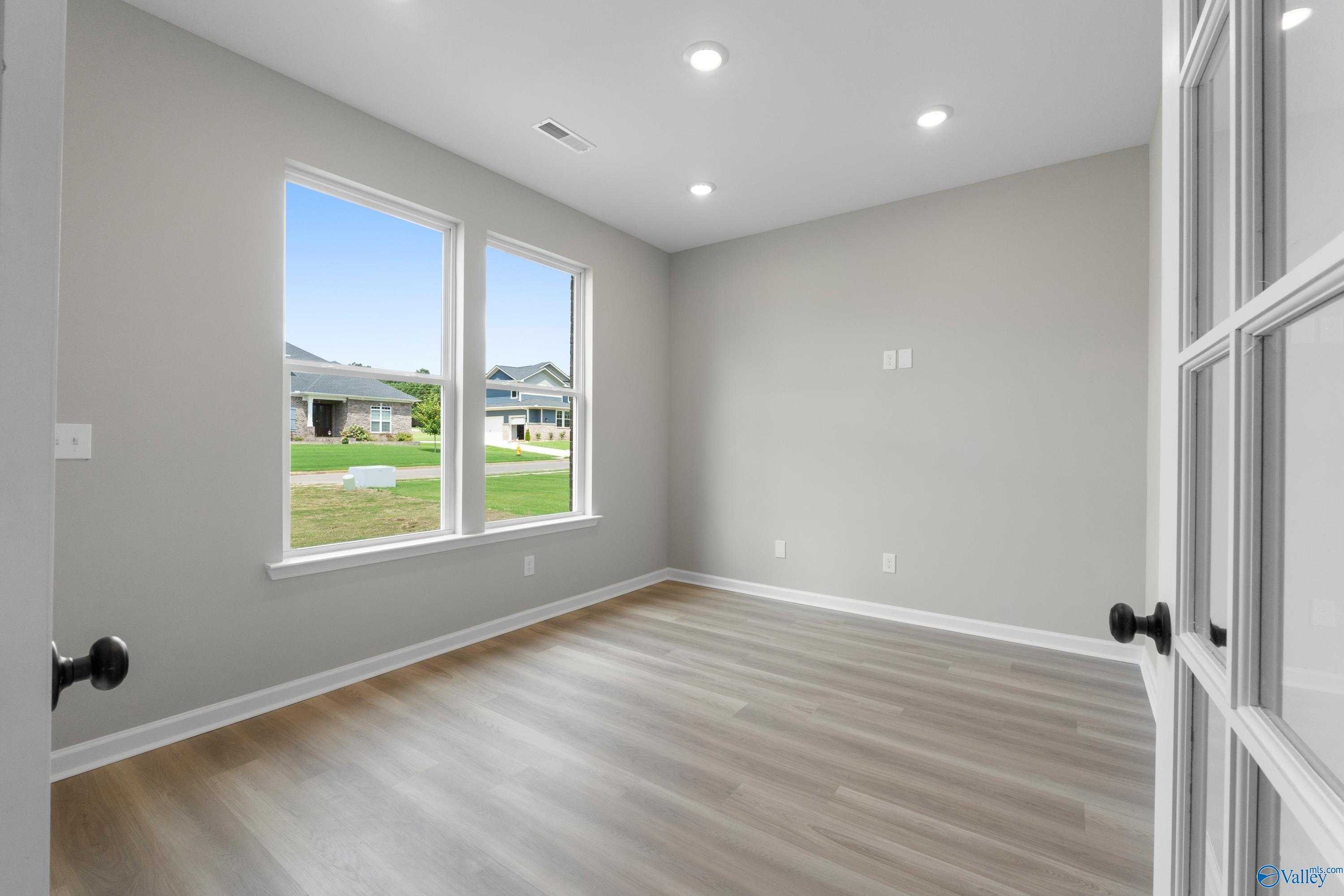Bright secondary bedroom with large windows, light gray walls, and laminate flooring in Davidson Homes Dorado, Huntsville AL