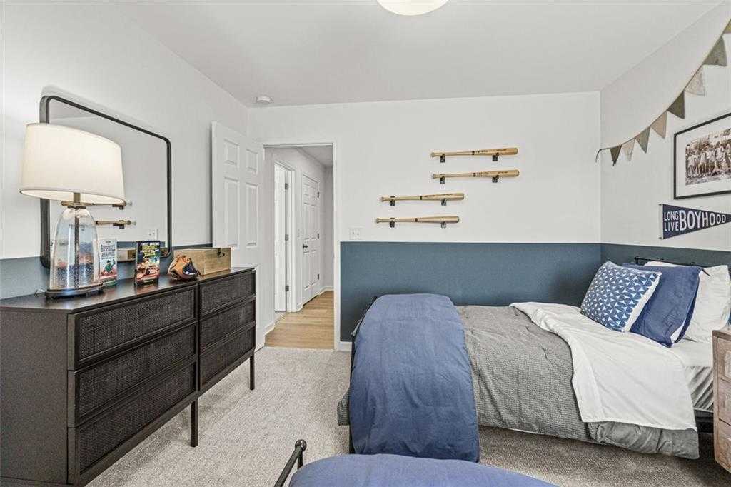 Cozy boy's bedroom with twin bed, navy bedding, dark dresser, and bamboo wall shelves in Davidson Homes The Hickory B plan, Hoschton, Georgia